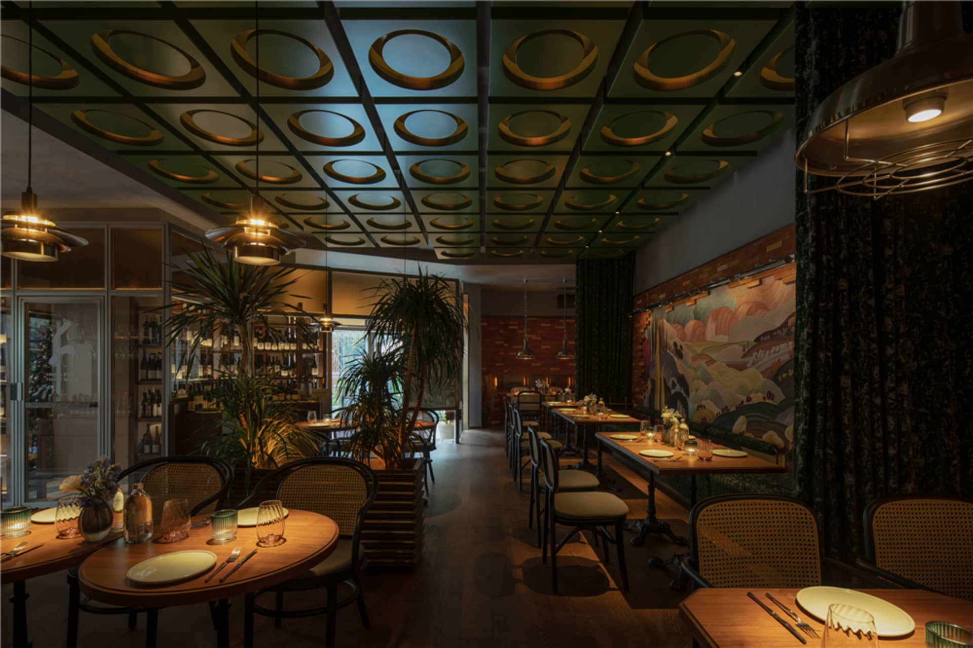 溫暖舒適的用餐空間，設有多張餐桌、椅子、盆栽植物，並以綠金色調為主