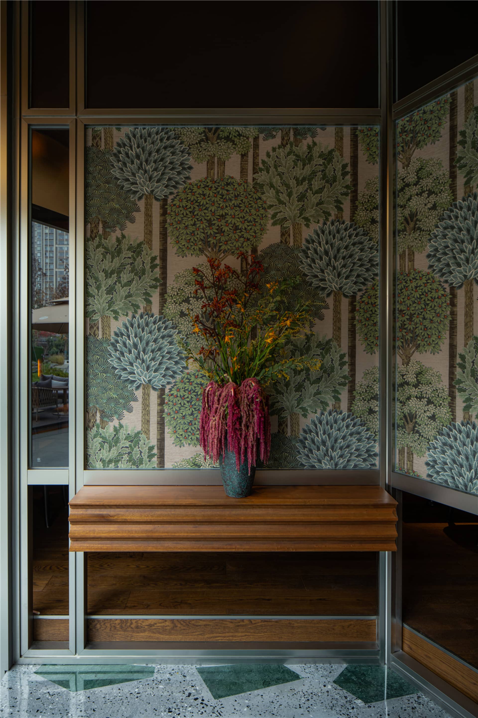 A cozy room with a wooden bench in front of a wall featuring a large floral print, set against a hardwood floor
