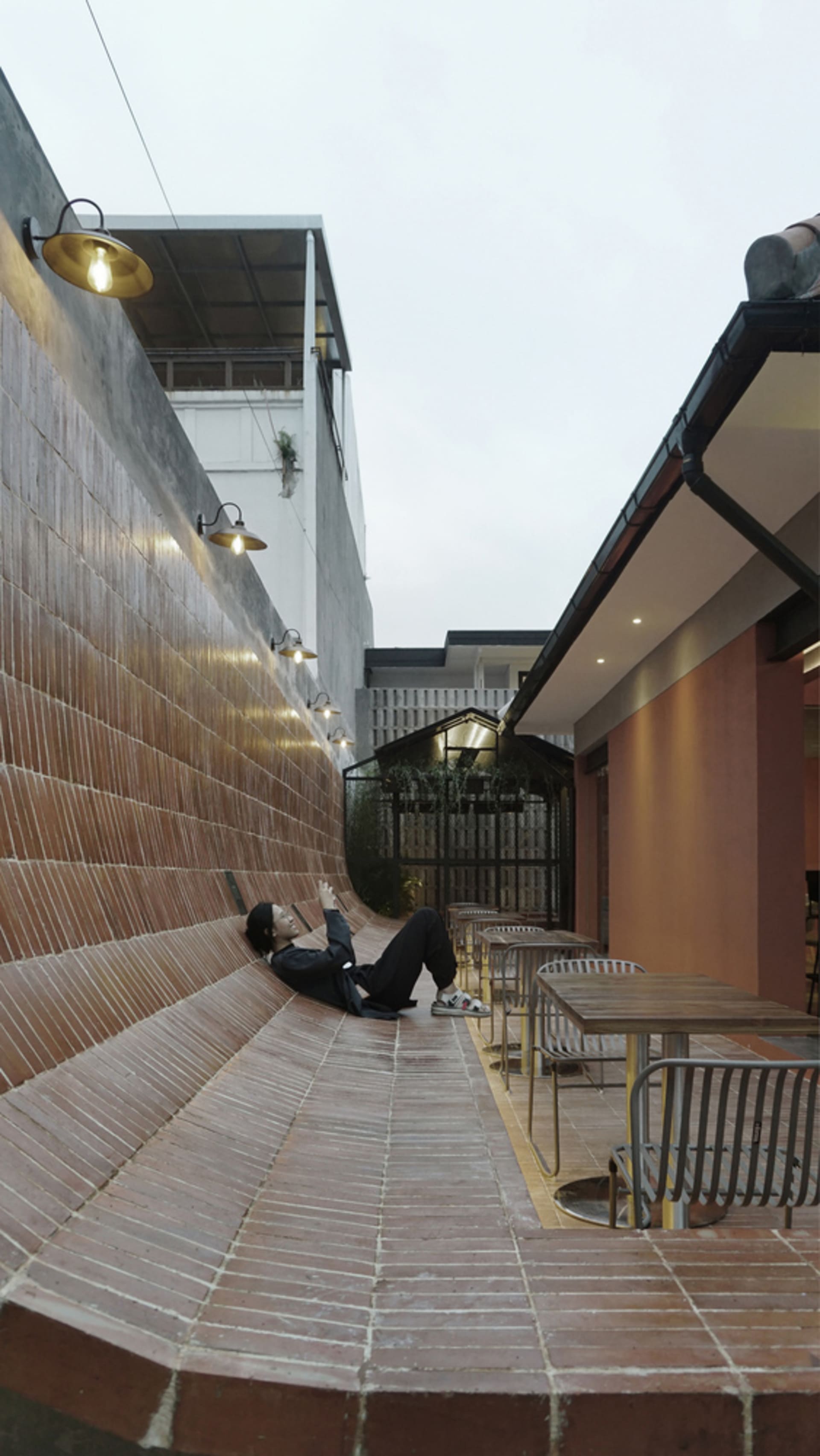 Relaxed outdoor dining space with a brick wall, stone bench, and multiple chairs in a natural setting