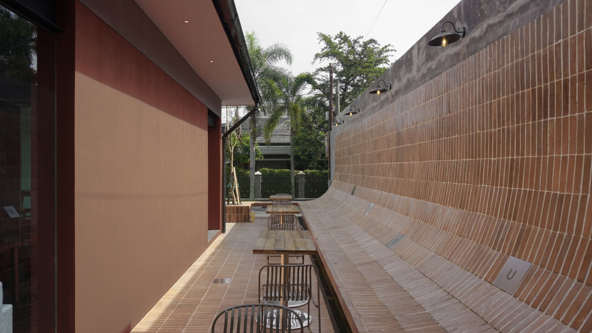 A casual restaurant patio with wooden benches and tables, chairs, and a relaxed atmosphere