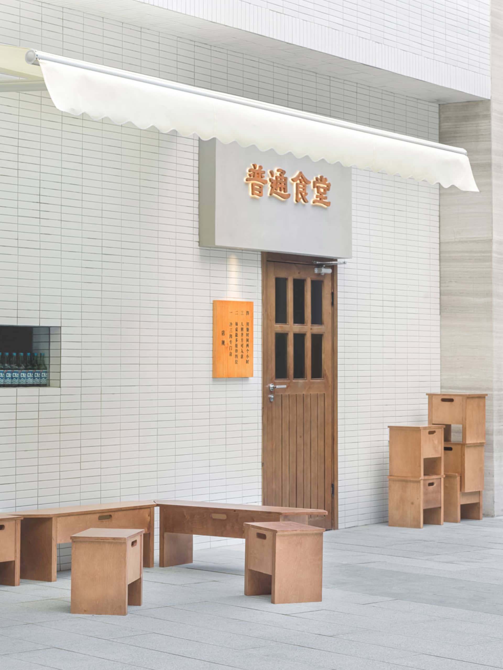 A traditional Asian restaurant with a white exterior, wooden doors, and outdoor seating with wooden tables and chairs, creating a welcoming atmosphere