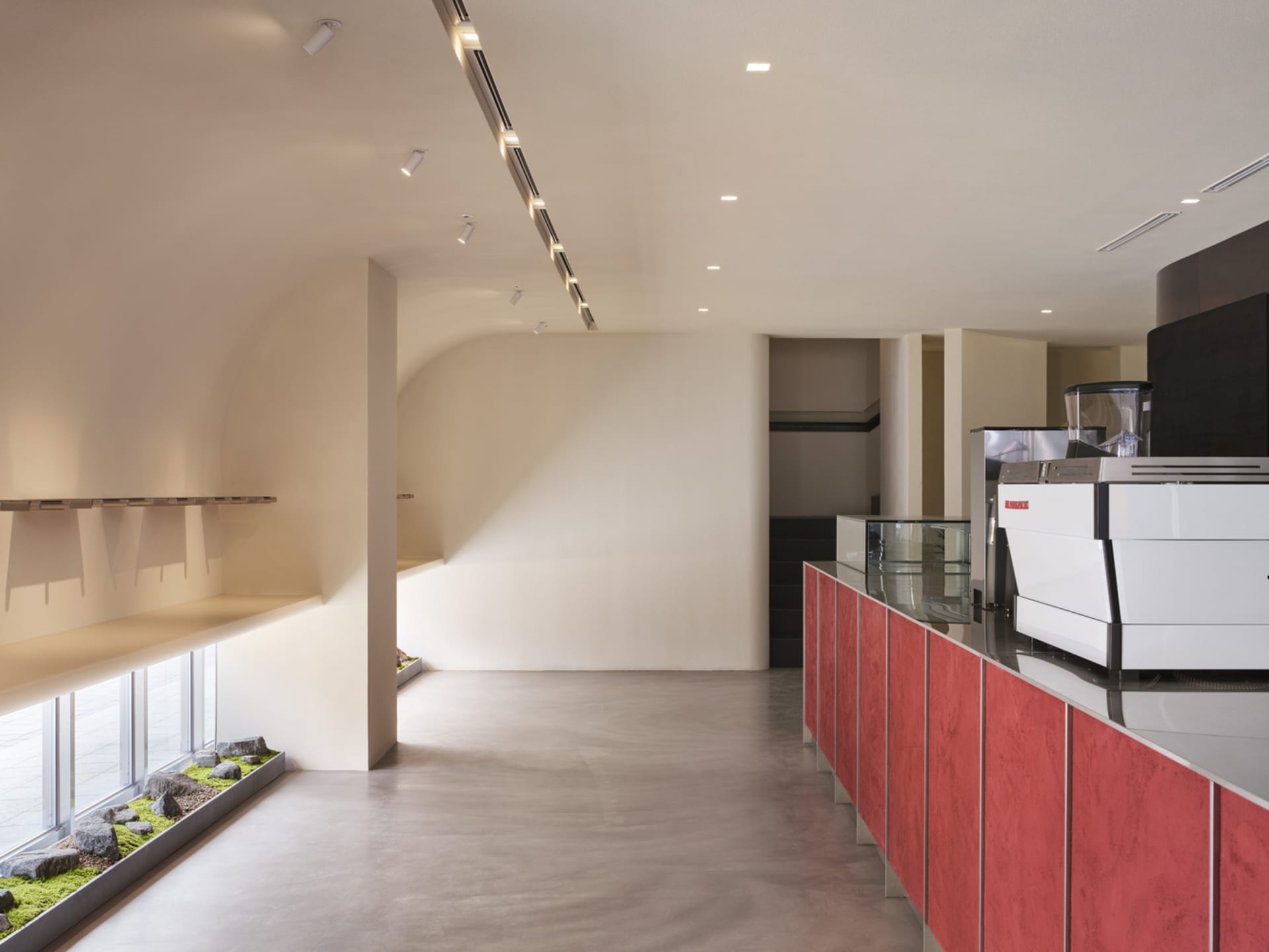 Modern kitchen with white walls, red cabinets, and two coffee makers on the countertop