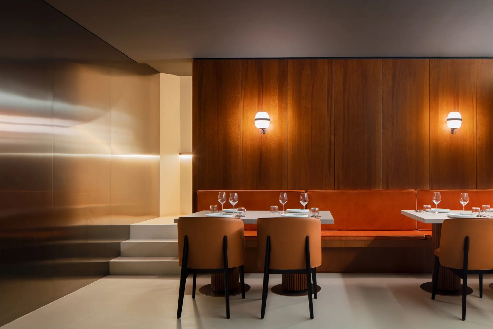 A cozy dining area with two long tables, wooden panel walls, and benches, set up for a meal or gathering