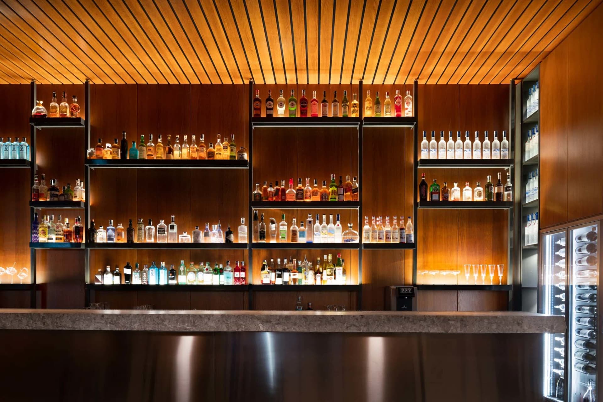 A well-stocked bar with a variety of liquor bottles displayed on shelves behind the counter