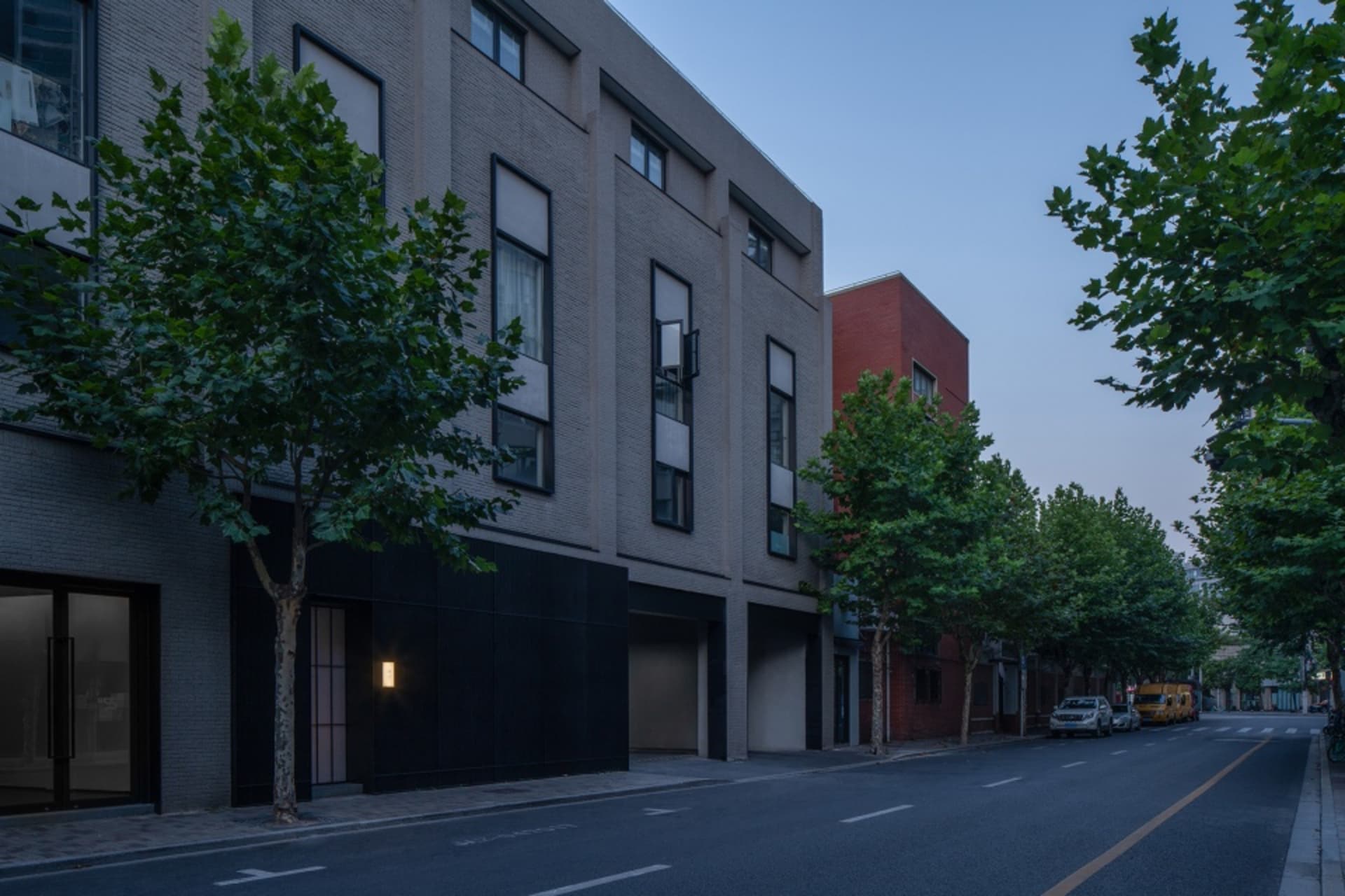 都市街景，兩棟大型建築物、汽車與卡車停在繁忙城市環境中的柏油路上