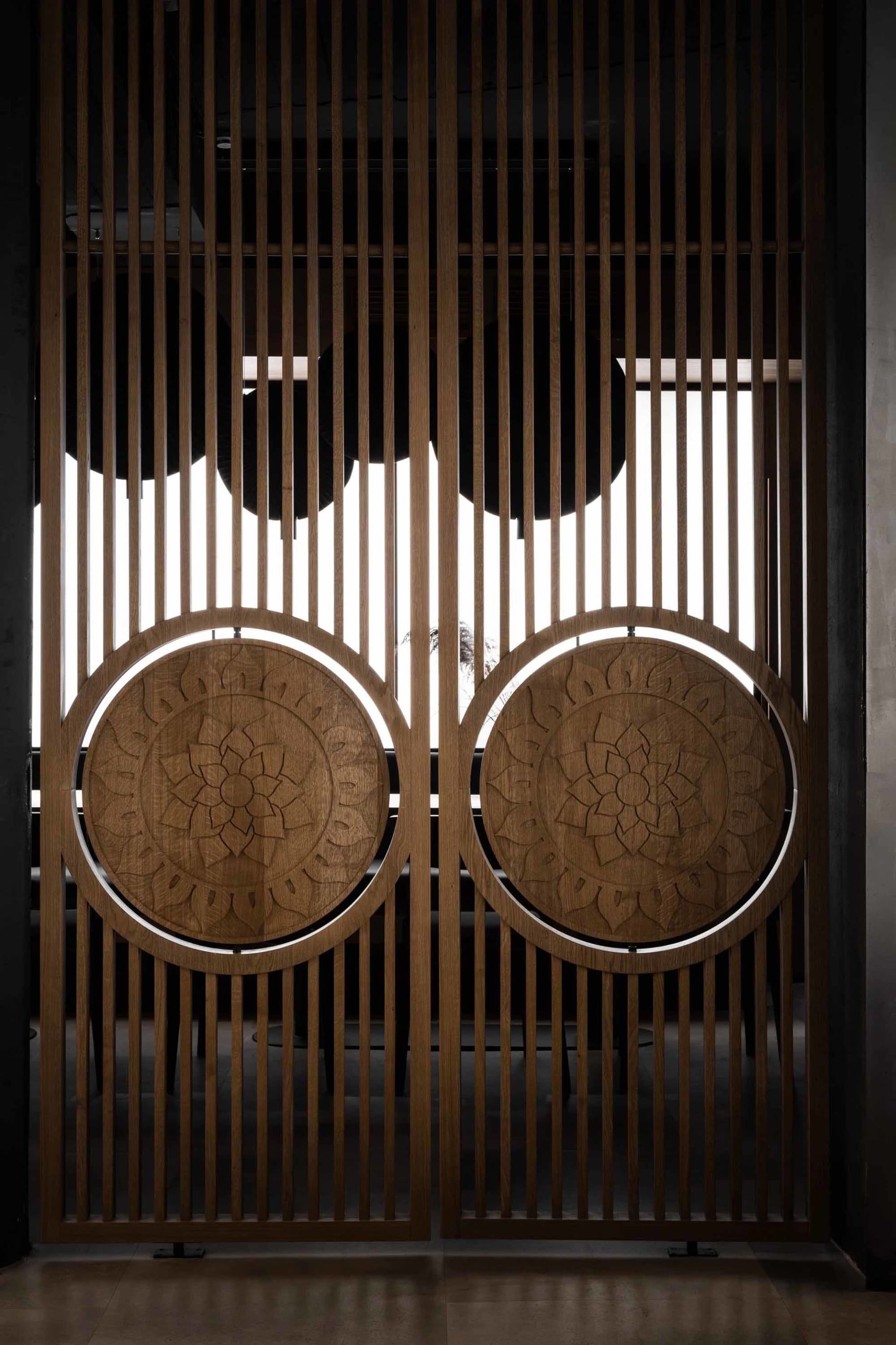 Elegant interior space with wooden doors featuring intricate carvings, open to reveal a view of another room
