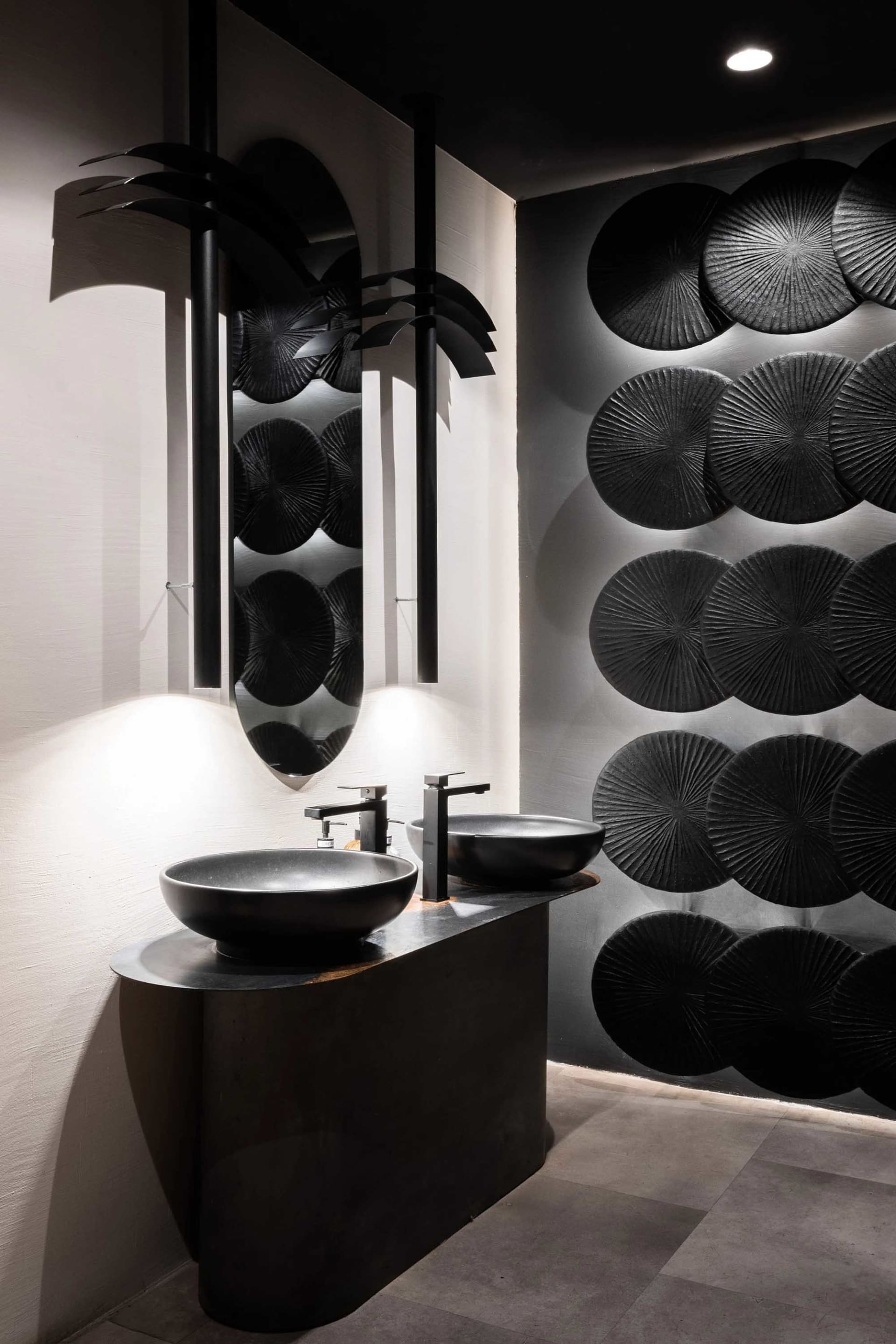 Bathroom with two sinks under a mirror, stone walls, and a large mirror above the sinks