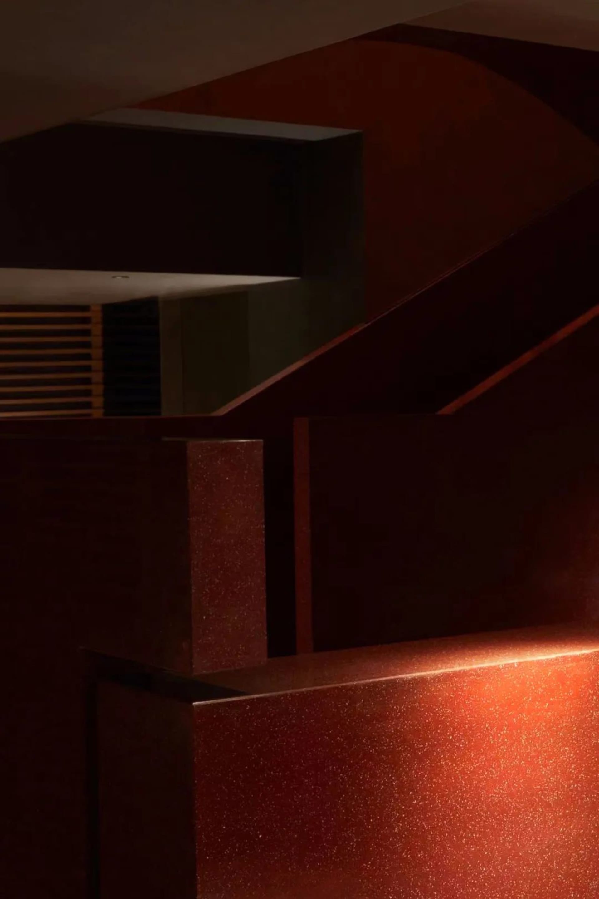 A dimly lit staircase in a house with red brick stairs, leading downwards