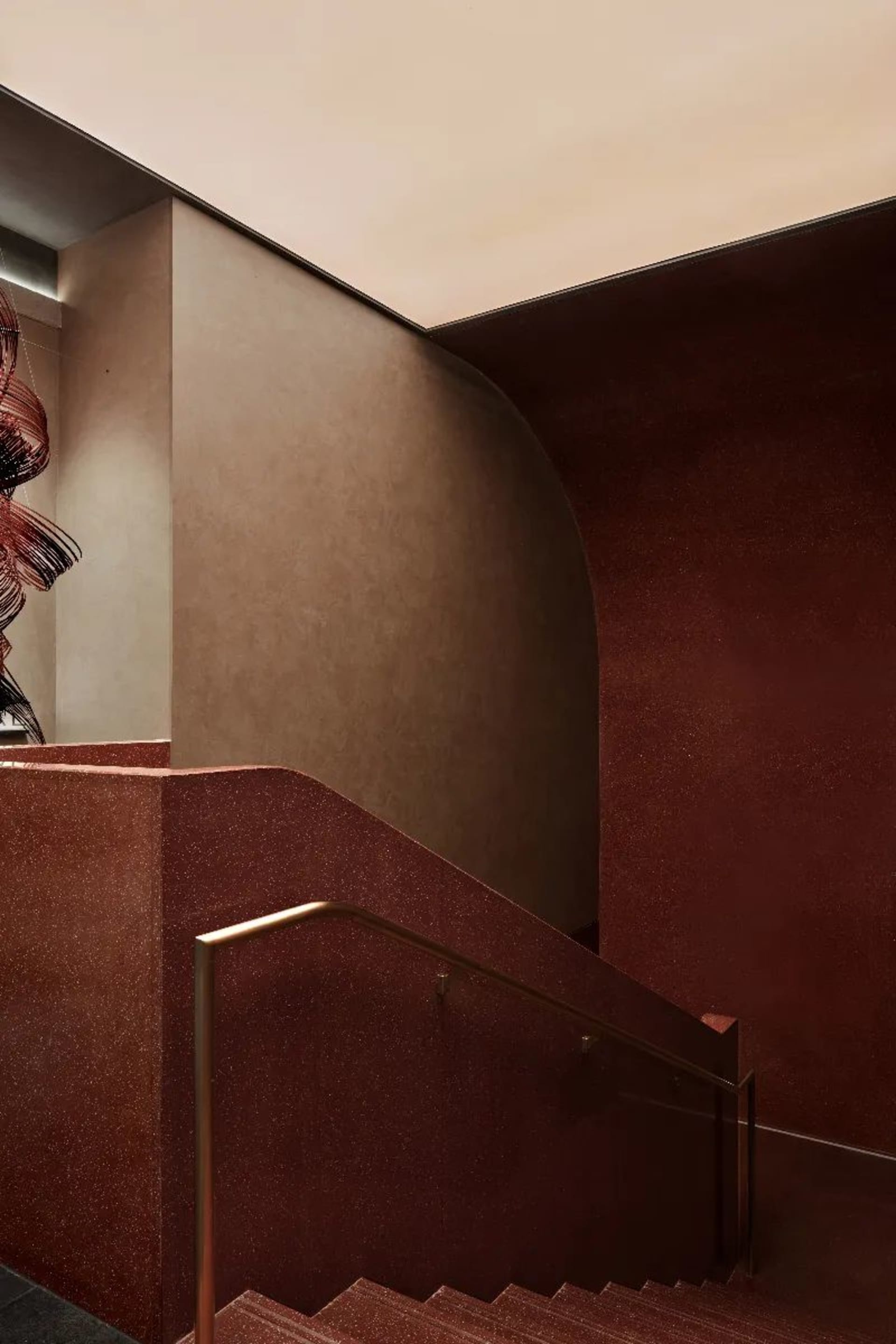 A grand staircase with marble steps and a red accent wall, set against a natural light-filled backdrop
