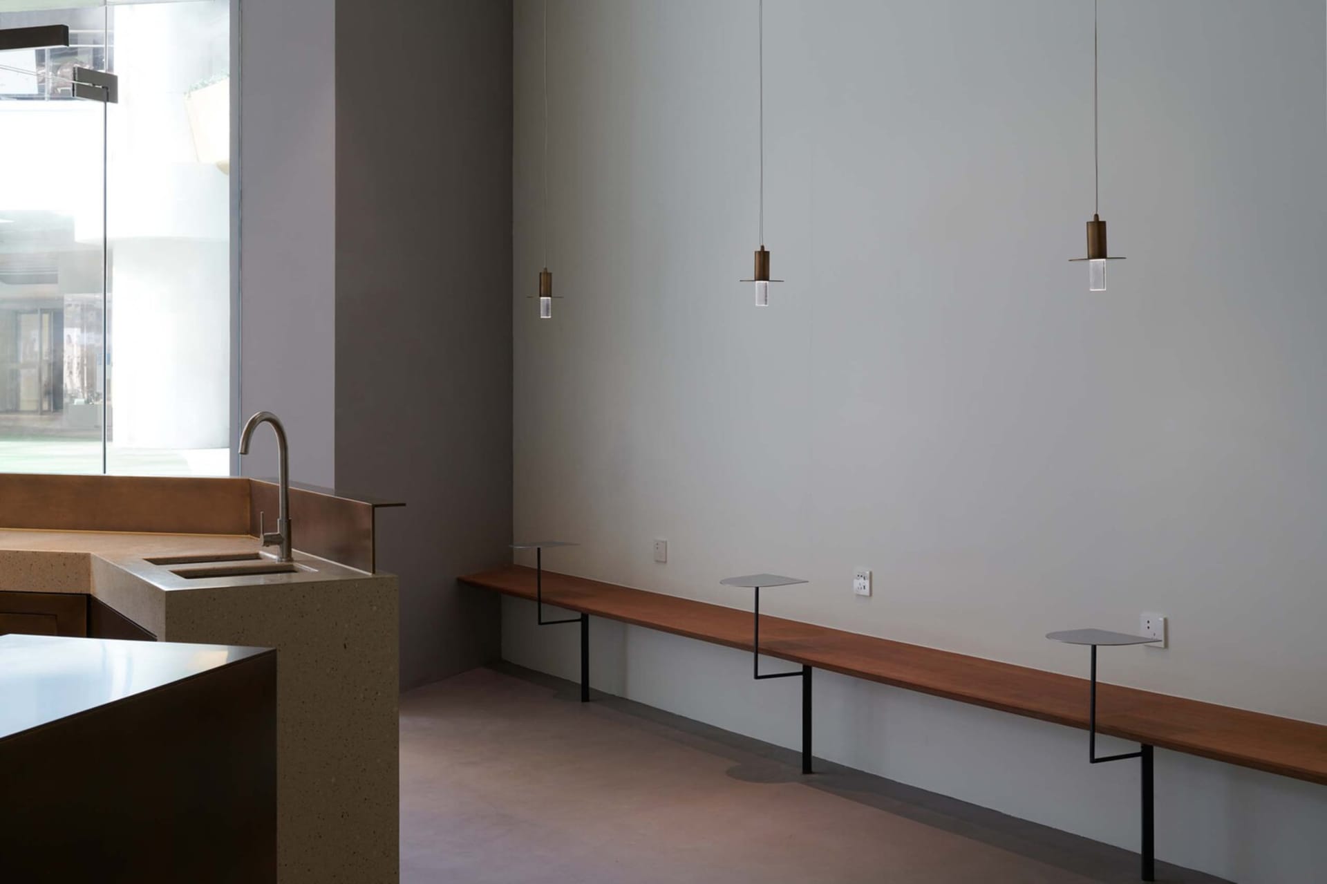 Empty kitchen dining space with a bench and sink, illuminated by pendant lights