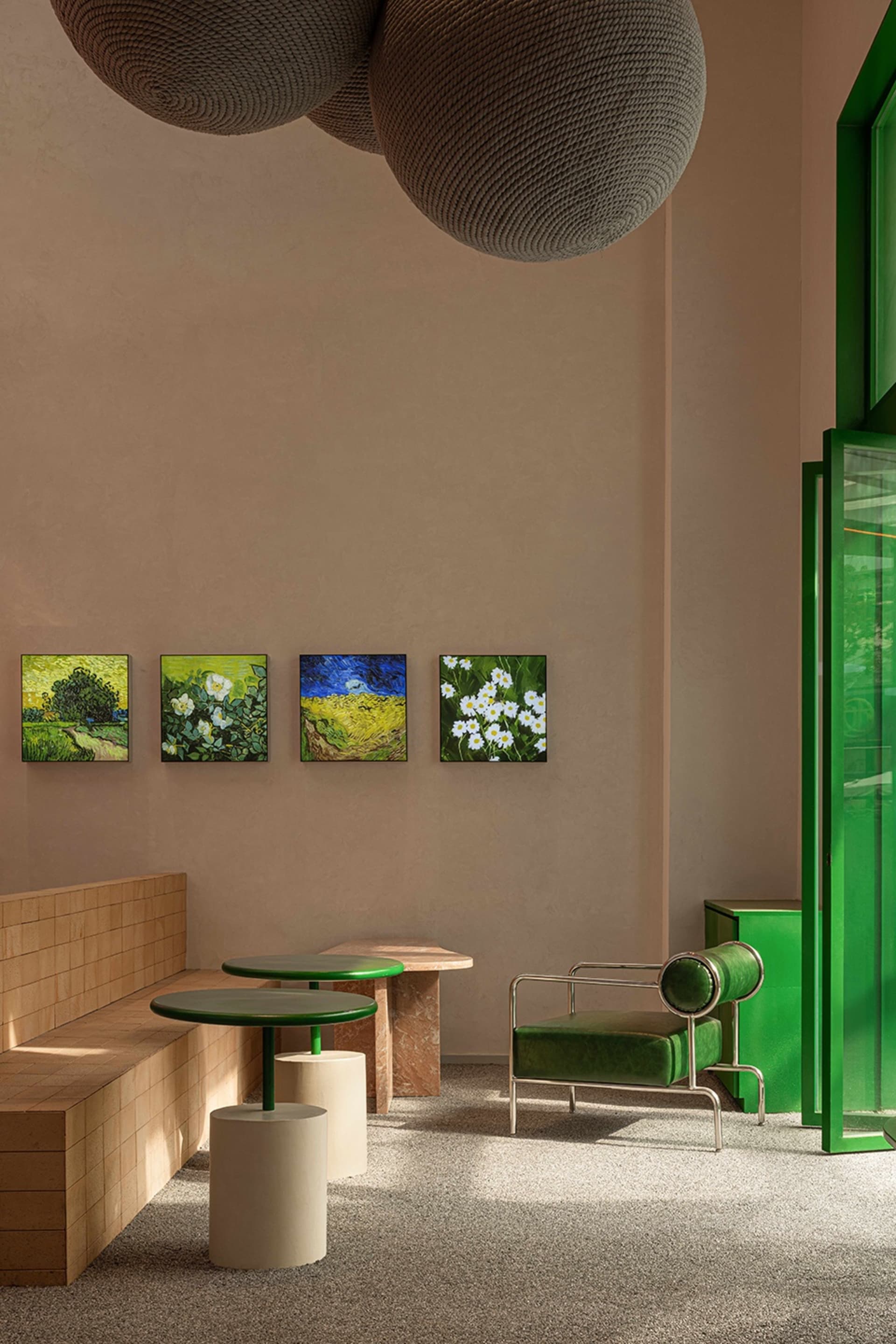 Cozy cafe with green walls, tables, and a couch, featuring artwork and comfortable seating options