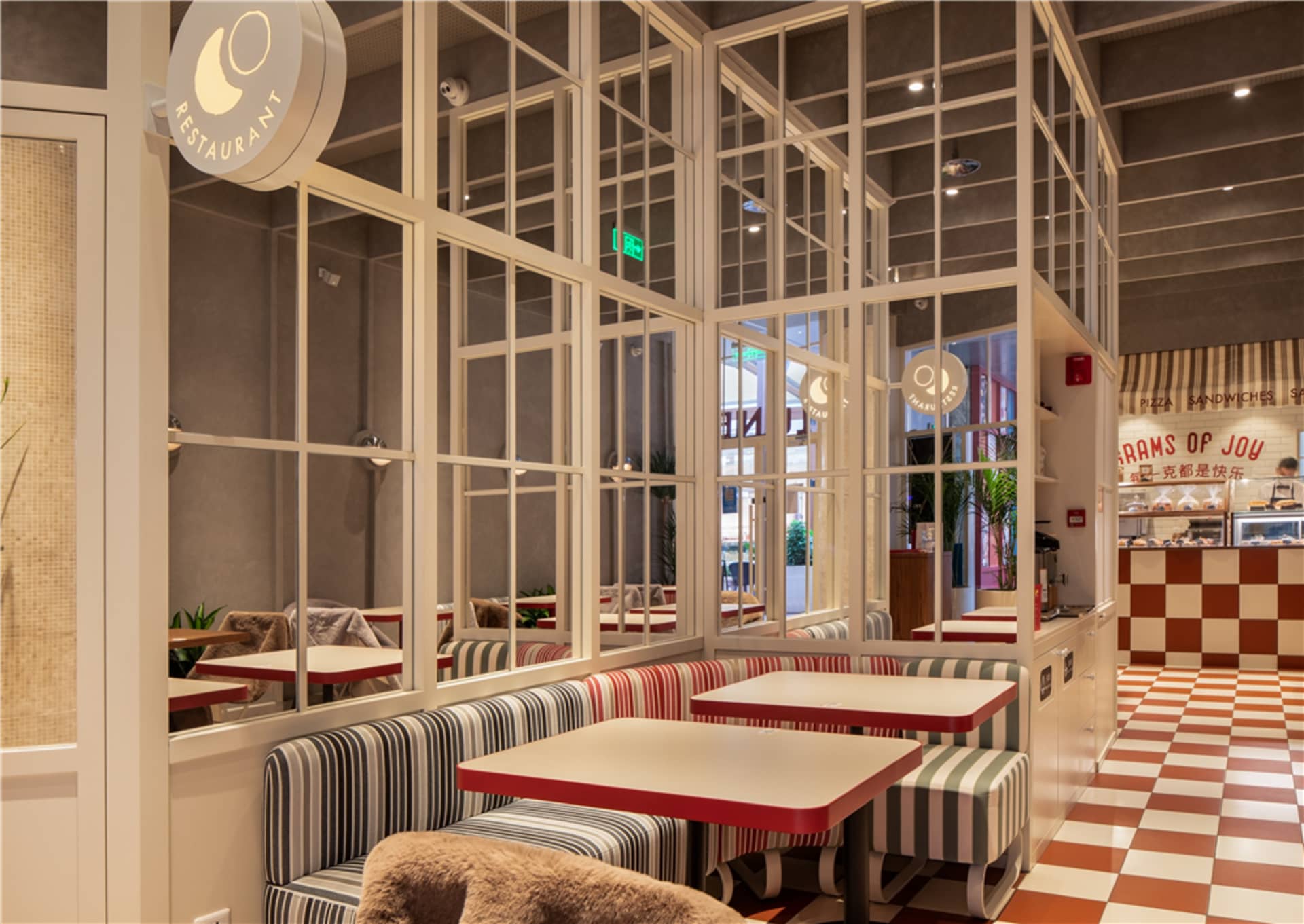 光線充足的餐廳，設有多張餐桌、椅子，以及大片窗戶讓自然光灑入空間