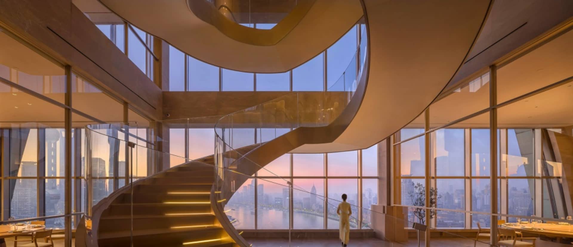 A spiral staircase with metal railings and a modern design, leading upwards in a luxurious setting