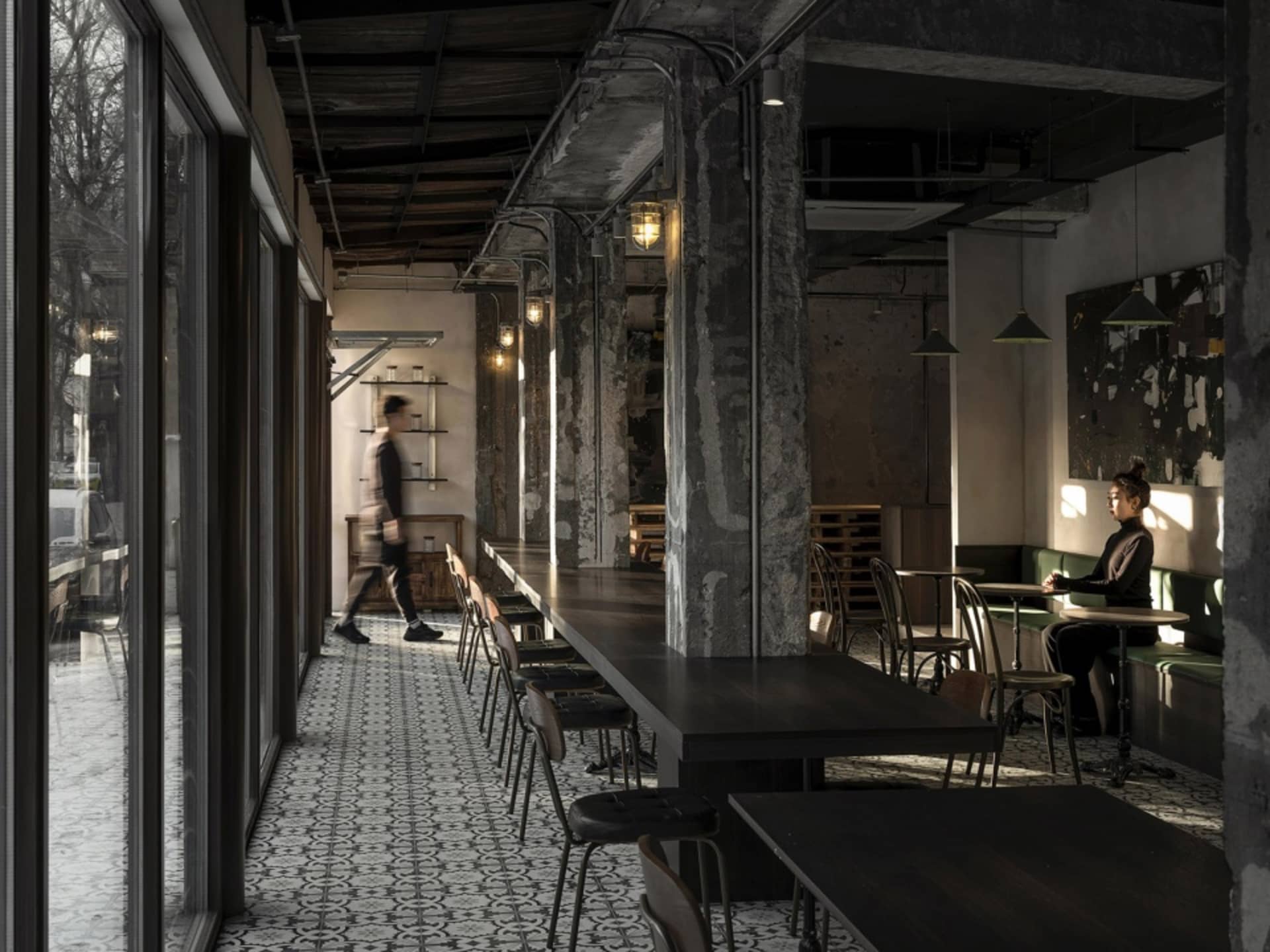 Industrial dining area with multiple tables and chairs, dimly lit with people present