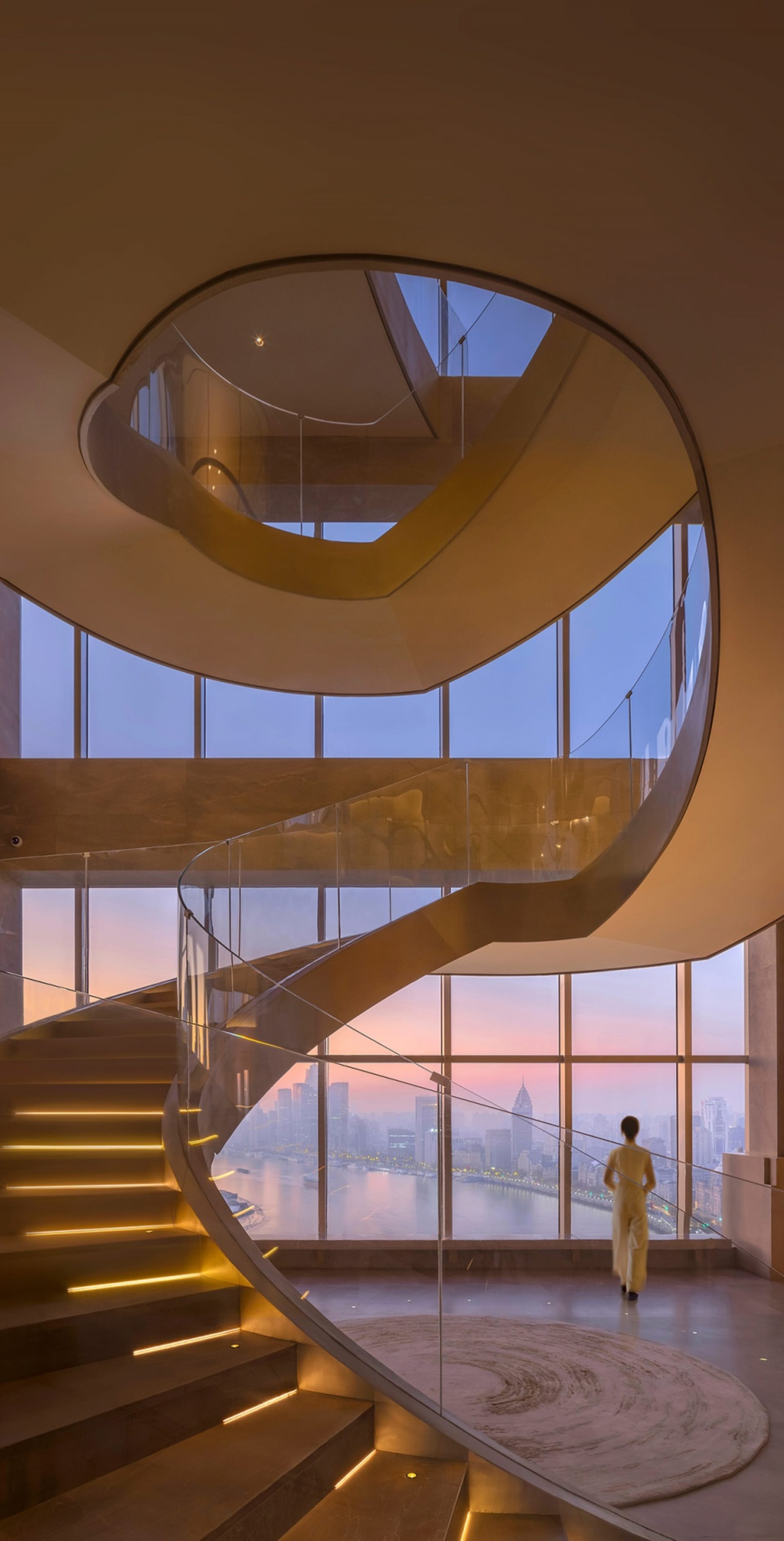A modern staircase with a glass railing in a well-lit, contemporary space with clean lines and minimalistic design elements