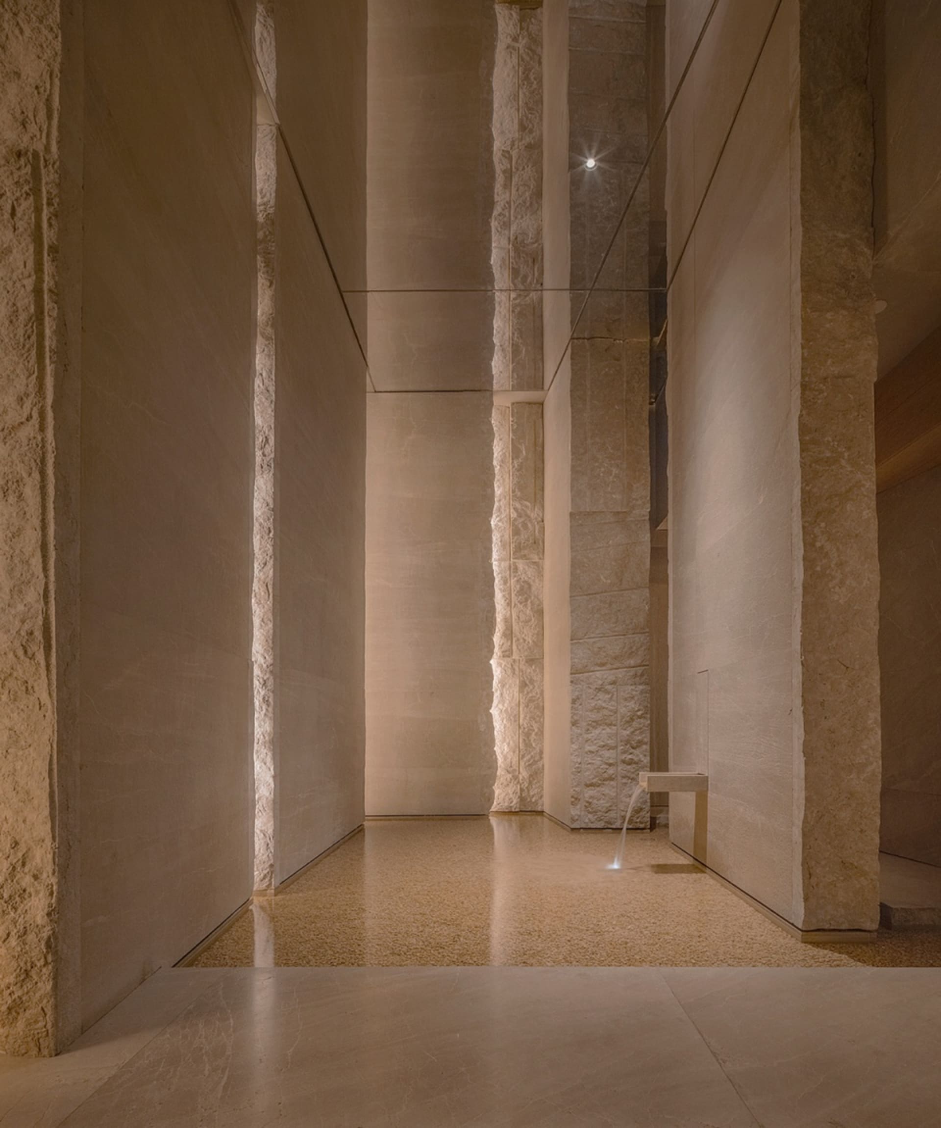 Empty lobby with a glass wall, two benches, and natural light creating interesting shadows on the walls and floors