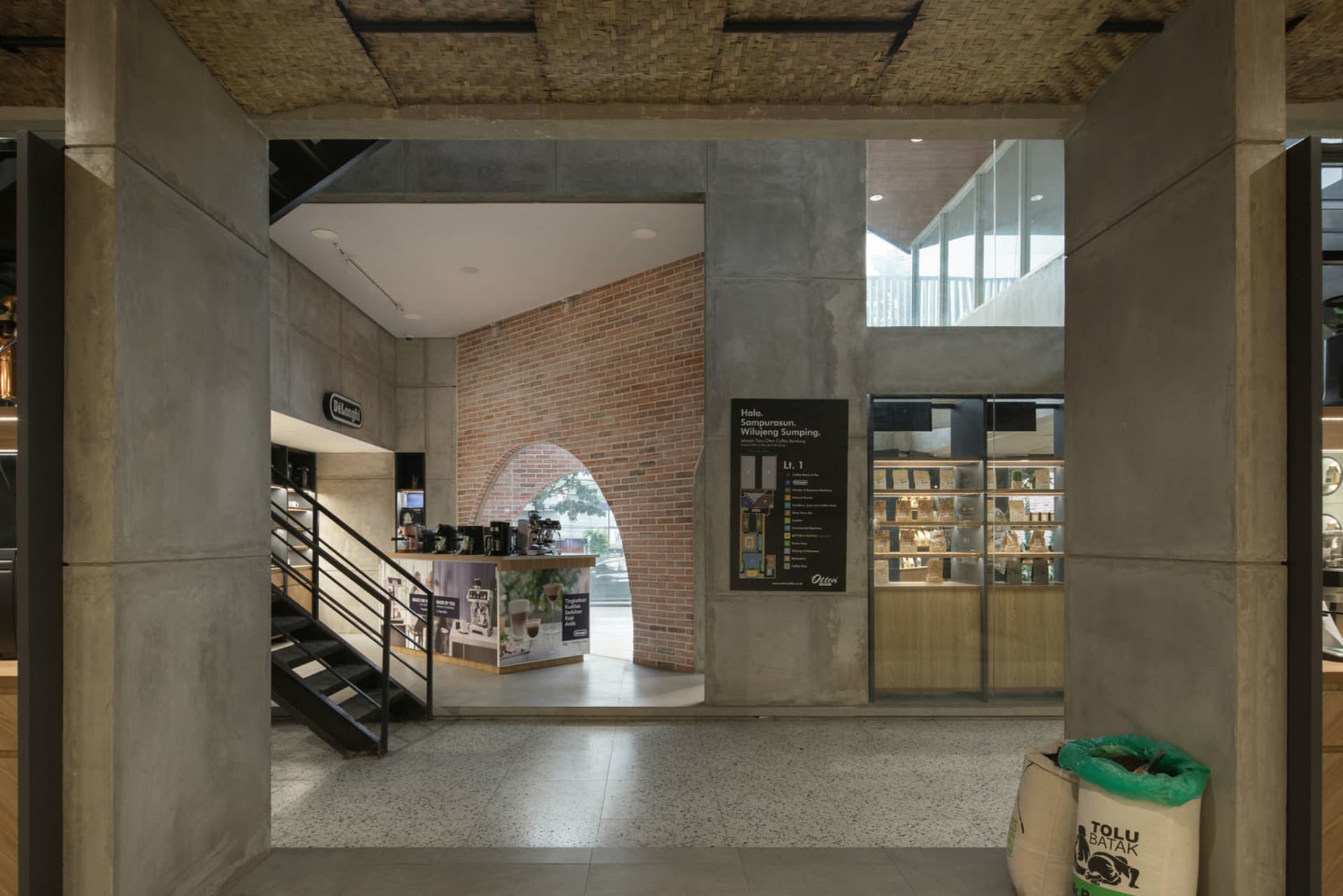 Open modern space with a concrete floor, a staircase, and large windows providing natural light