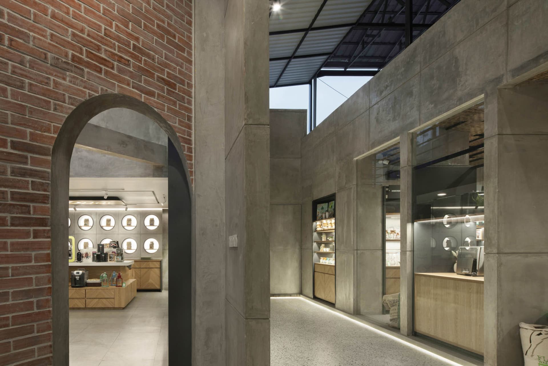 Open modern kitchen and dining area with a large brick wall, various kitchen appliances, and multiple chairs, with scattered bottles and a contemporary feel