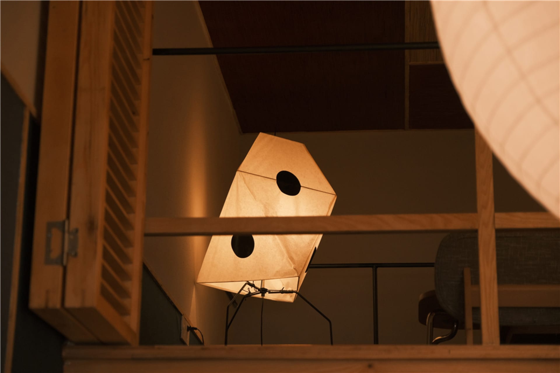 A dimly lit room with a chair in front of a window, natural light illuminating the space, and two lights on the left and right sides