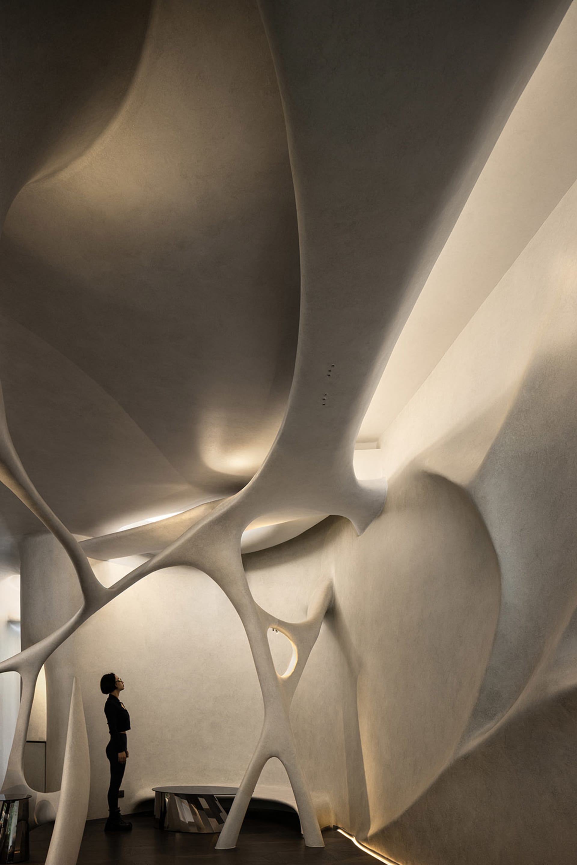 Contemporary interior design featuring a large white wall with a unique curved structure, a focal point in the room, with two people present