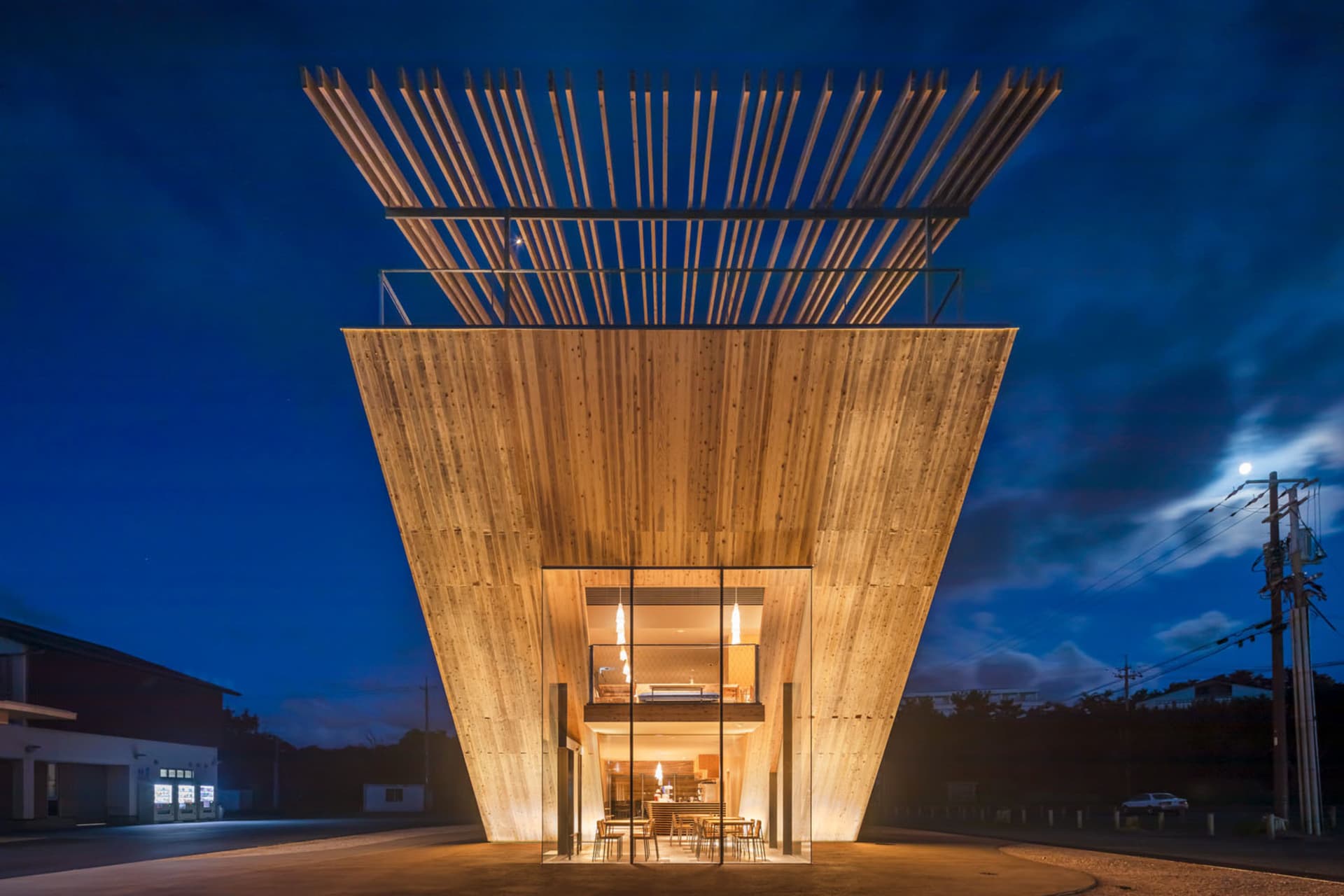 A modern dining space with a wooden structure, warm lighting, and a cozy atmosphere, featuring a dining table and chairs