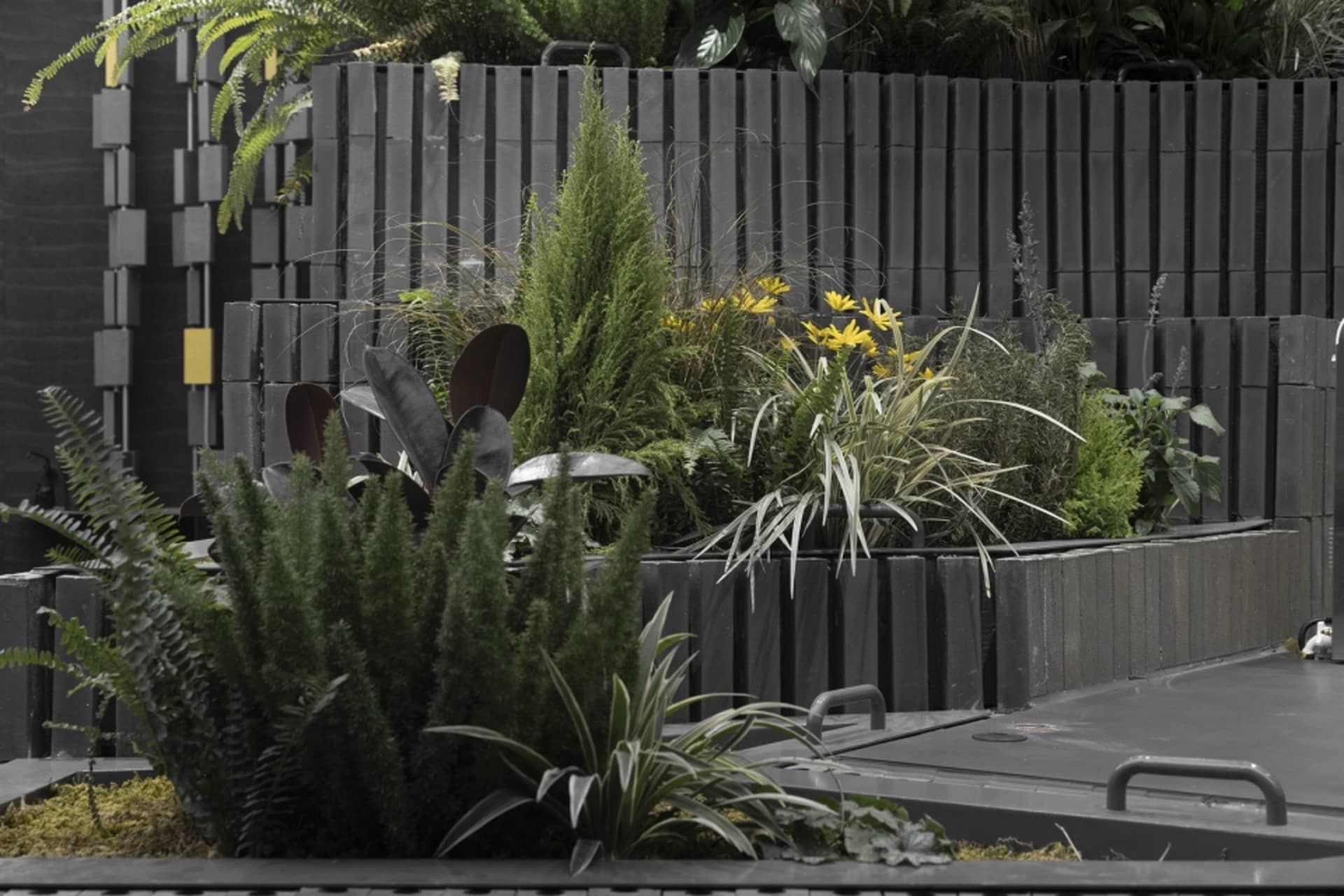 A serene indoor garden area with various plants in pots and a small waterfall, creating a lively atmosphere for relaxation and nature appreciation