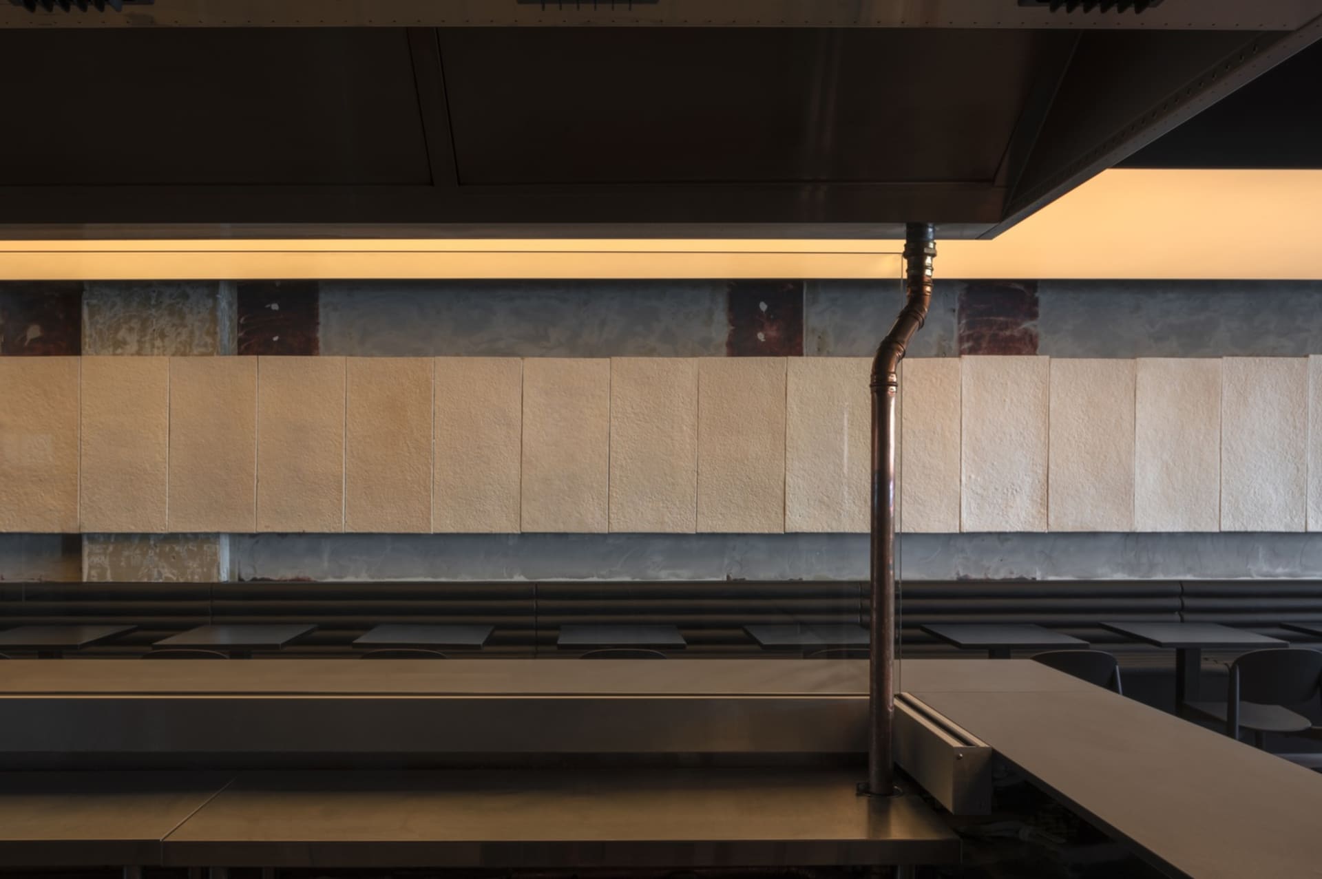 Industrial kitchen with a stainless steel countertop, metal pipe, and granite surface, featuring a modern and functional design