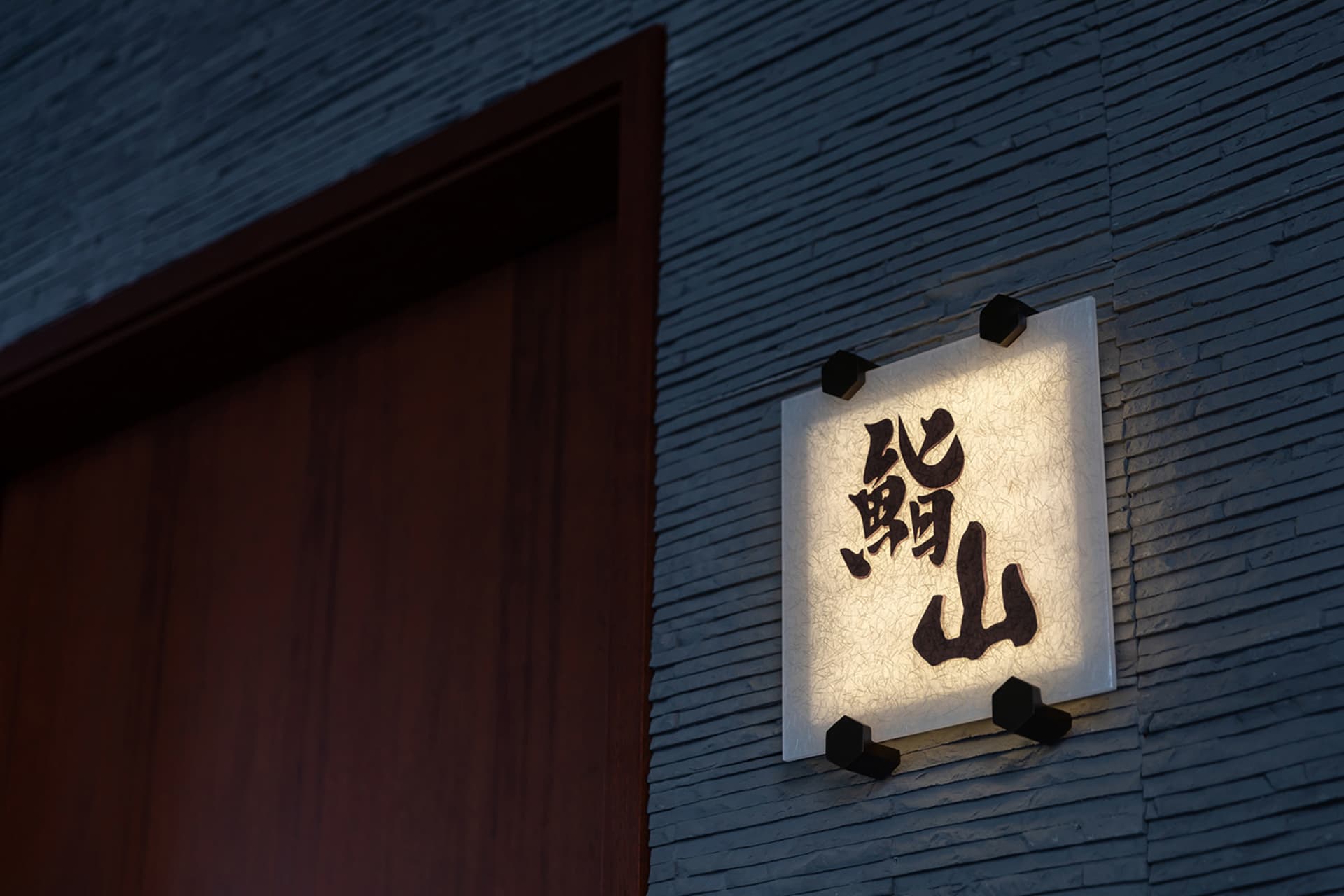 一棟傳統亞洲建築，配有木門與刻有漢字的石碑，襯托文化背景