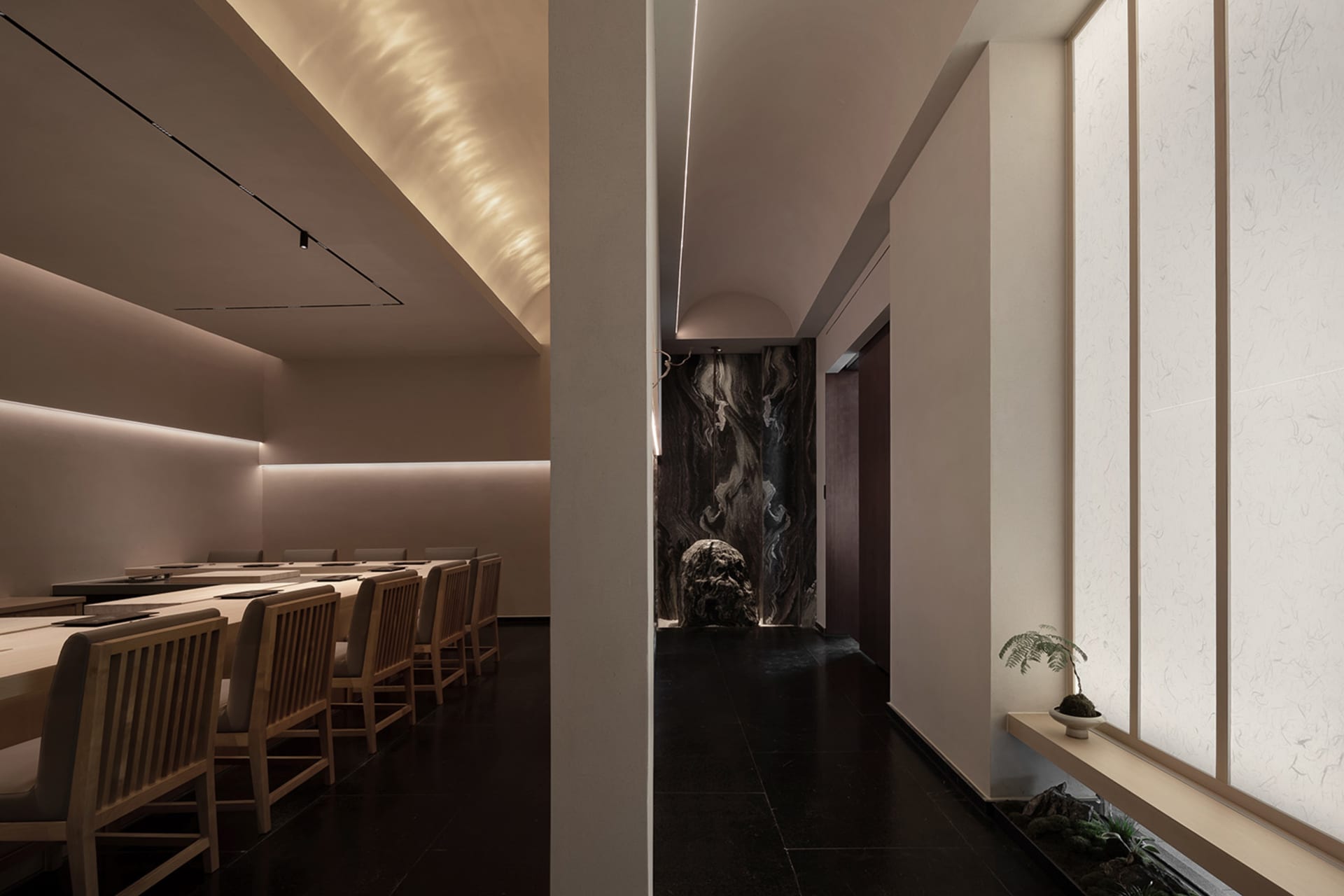 燈光柔和的餐廳用餐區，配有椅子、餐桌與牆面大理石點綴