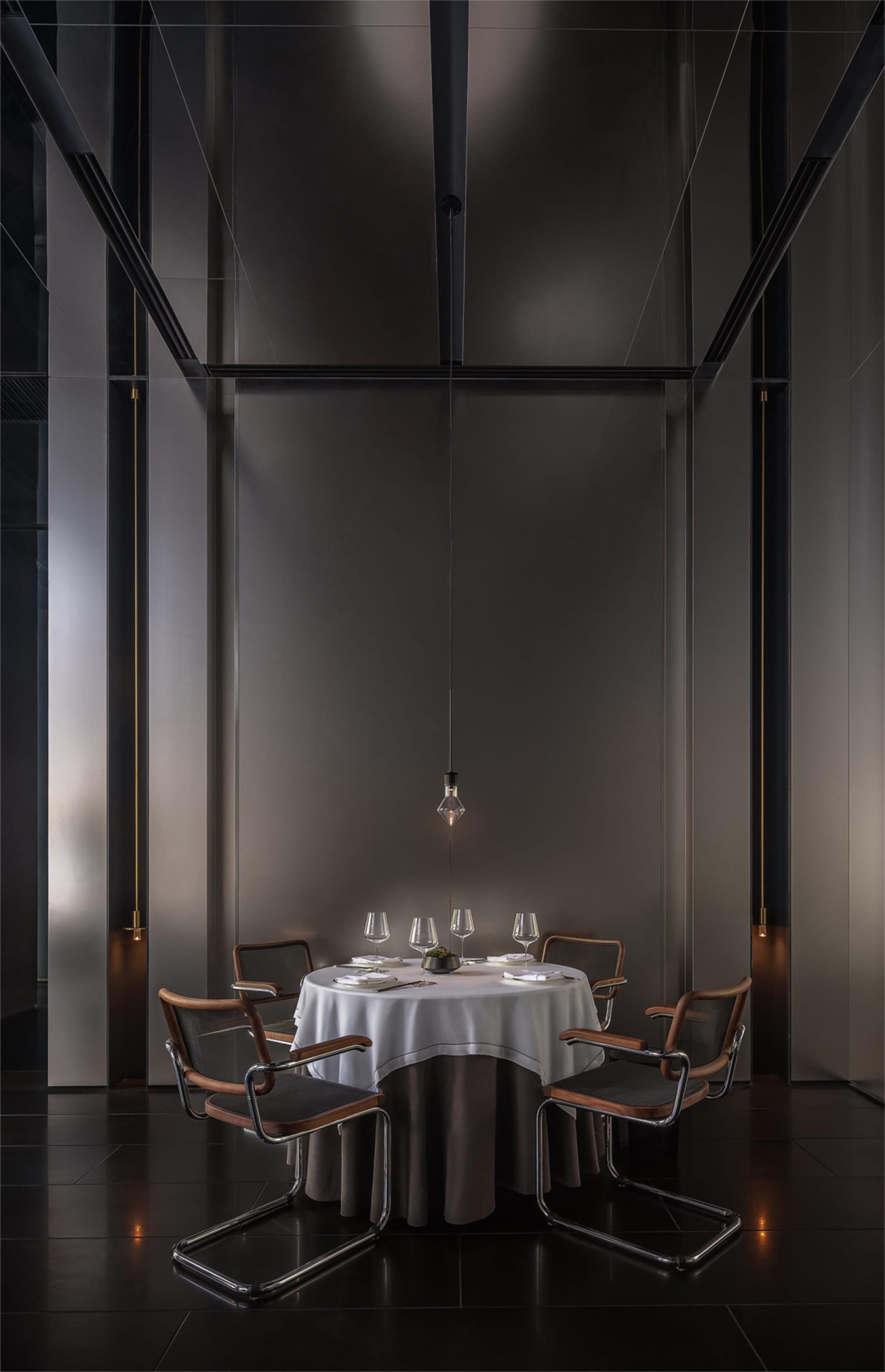 A modern dining space with a wooden table and chairs, set with wine glasses, creating a sophisticated atmosphere