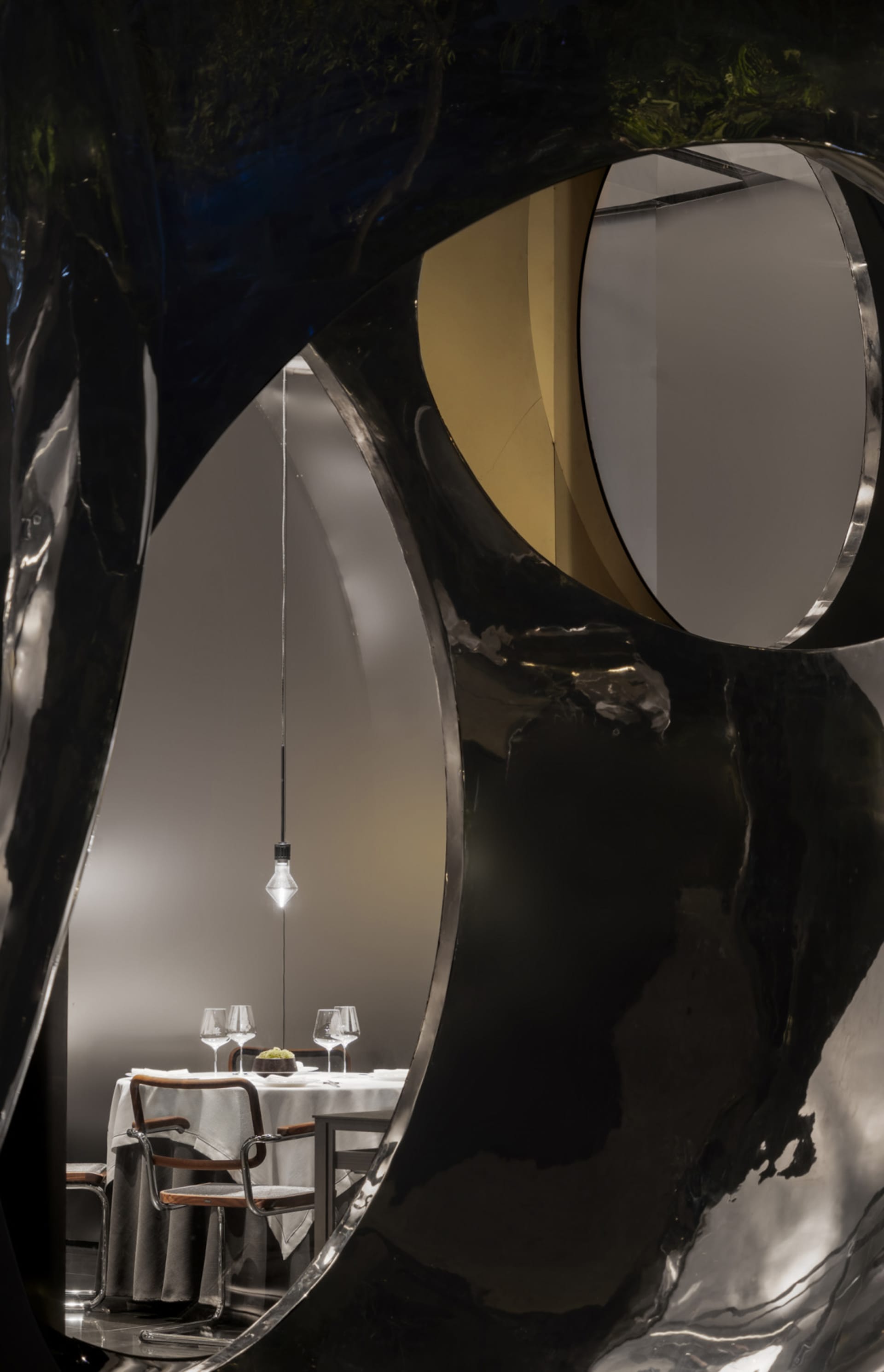 Dining area with a modern table and chairs, surrounded by black and white walls and a bowl and wine glasses on the table