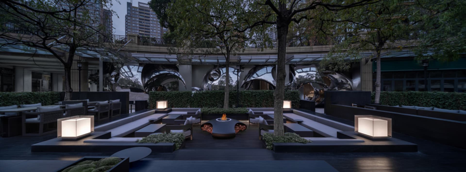 A patio area with chairs and dining tables arranged around a fire pit, creating a cozy and inviting atmosphere for gatherings and social events