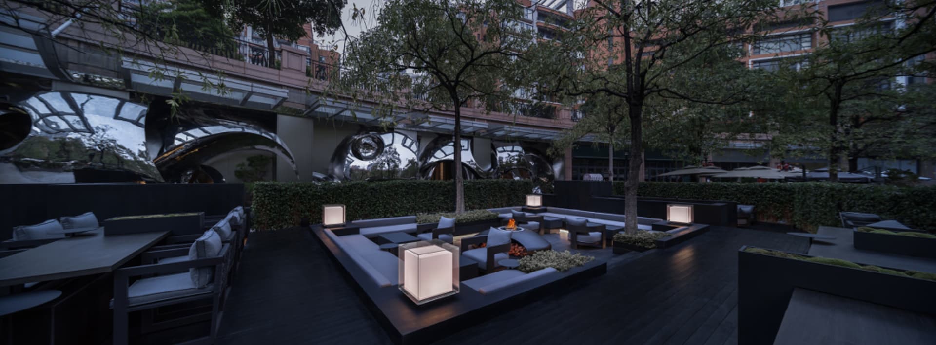 A relaxed outdoor patio scene with a fire pit surrounded by chairs and dining tables, perfect for social gatherings or warm evenings