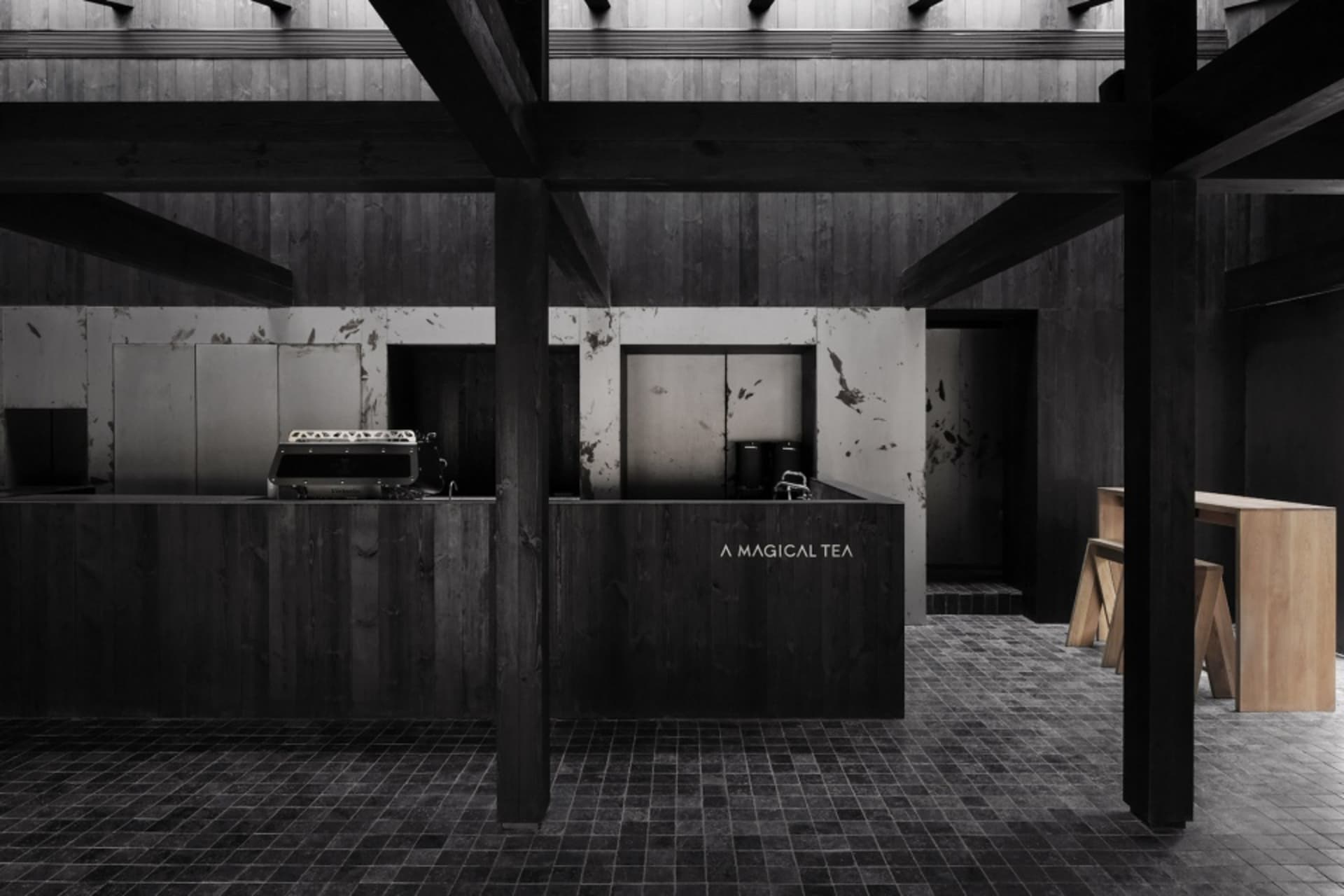 A dark and mysterious kitchen with a black and white photo aesthetic, featuring a countertop, sink, oven, and refrigerator, with two chairs in the room