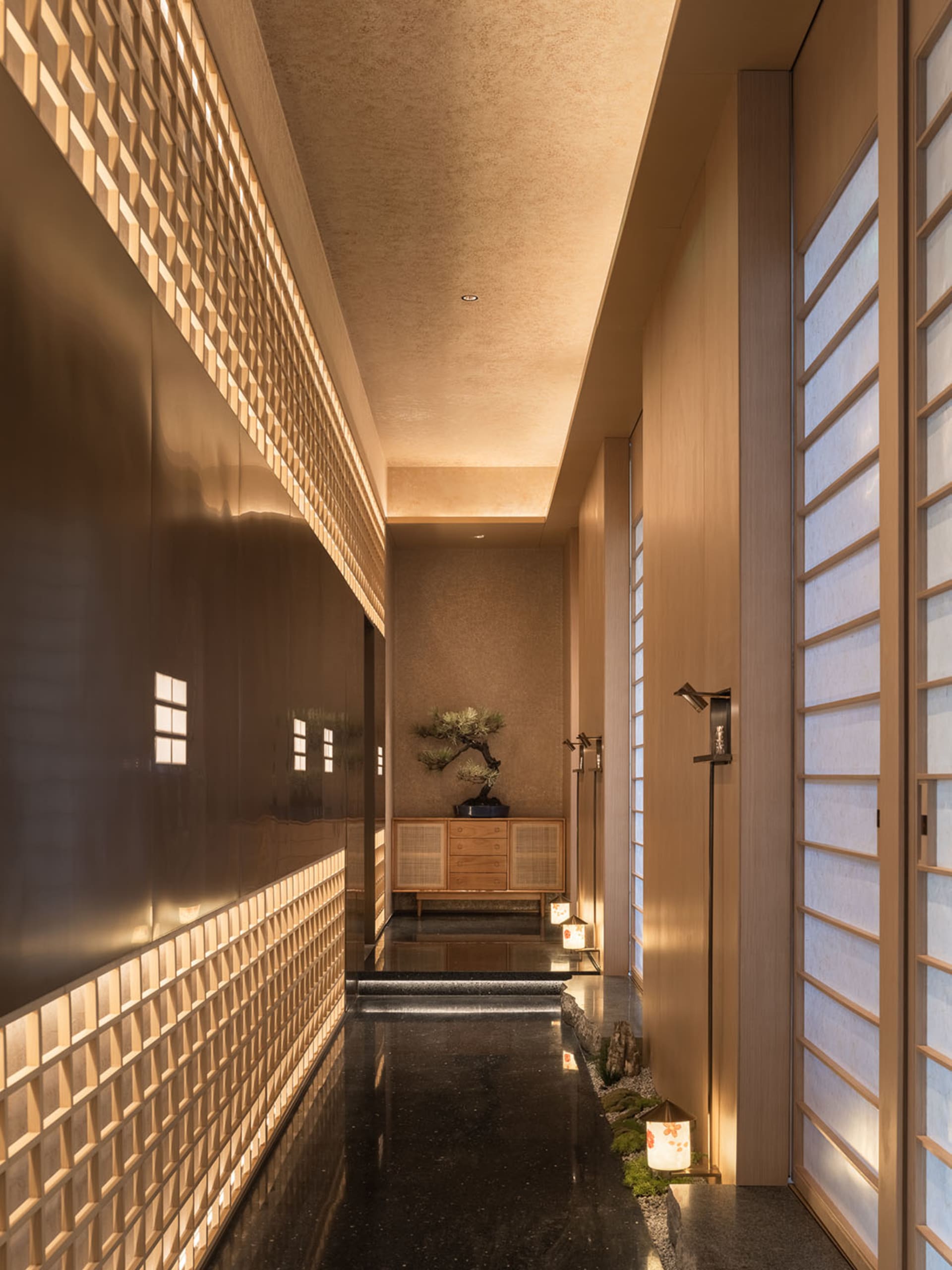 Elegant bathroom with black marble floor, modern design, natural light, potted plants, and decorative vases