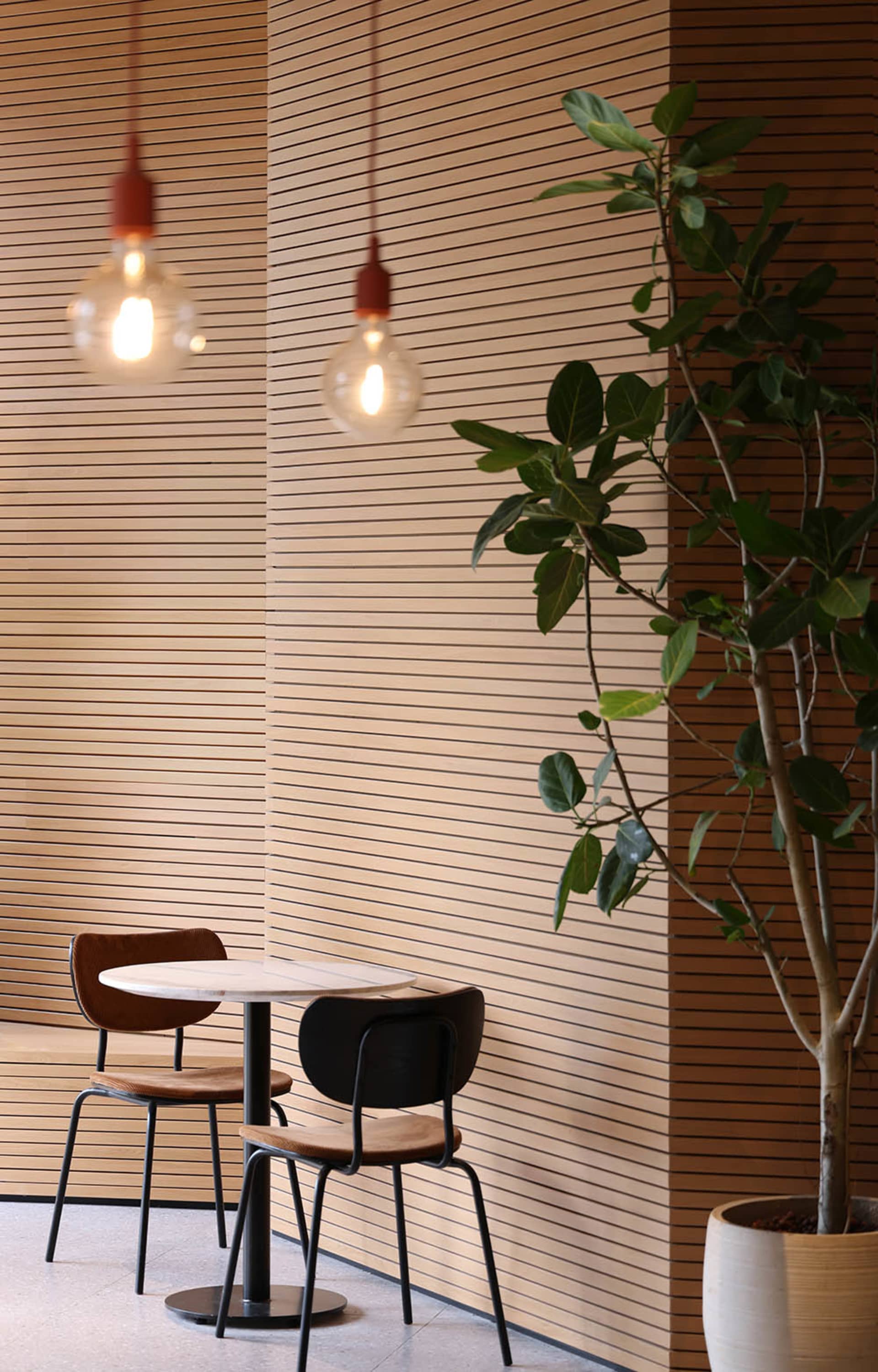 Cozy dining area with wooden paneling, two chairs, and a small table, lit by three lights