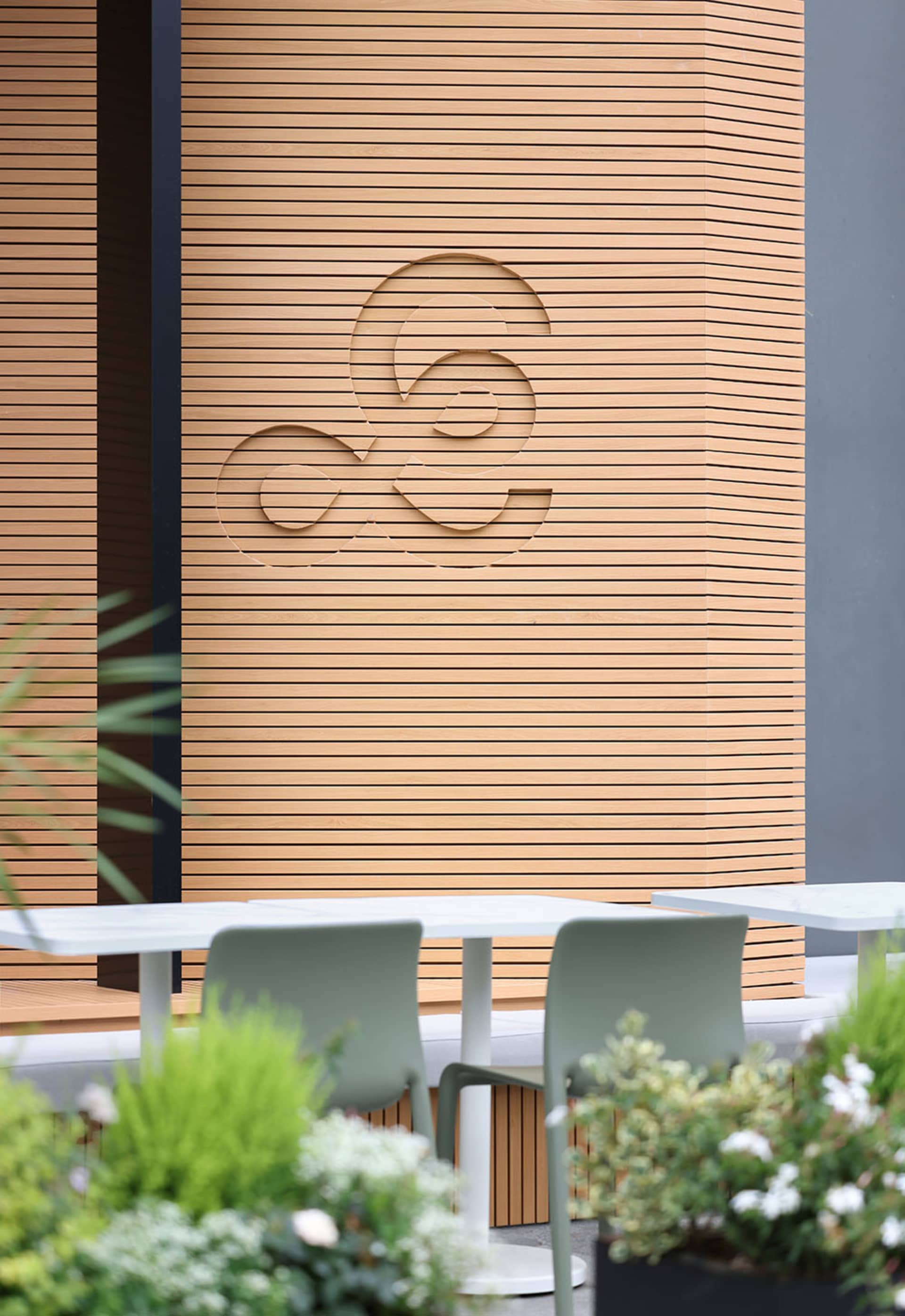 Warm and inviting dining space with wooden walls, a table, and two chairs, featuring a logo on the wall