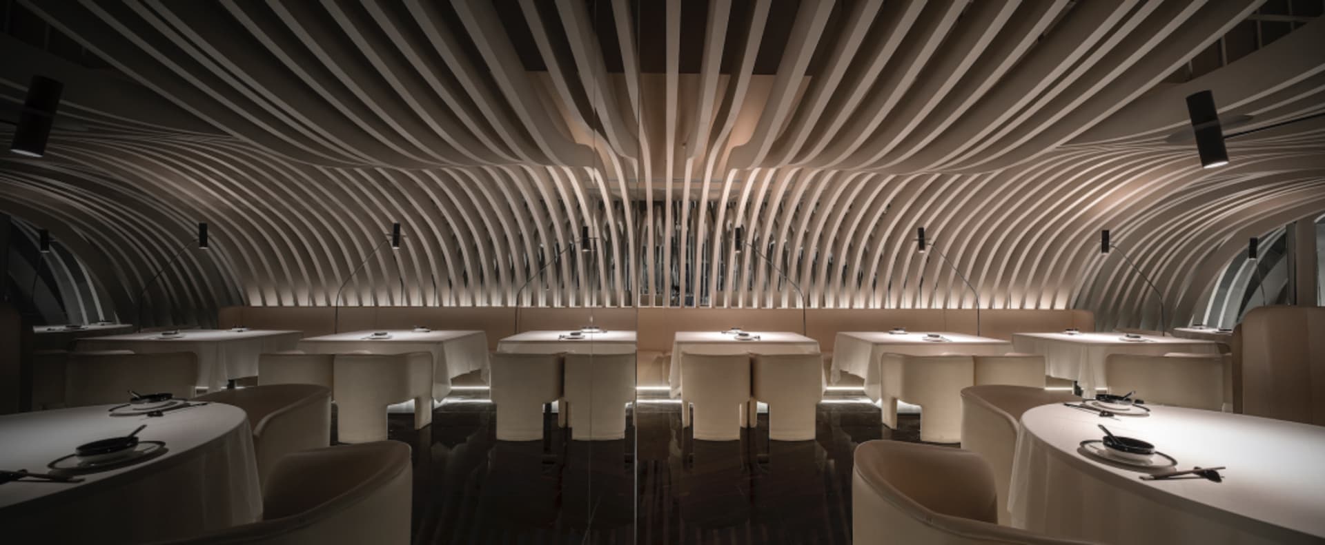A modern restaurant interior with white tables and chairs arranged in rows, creating a spacious and inviting atmosphere with clean lines and minimalistic elements