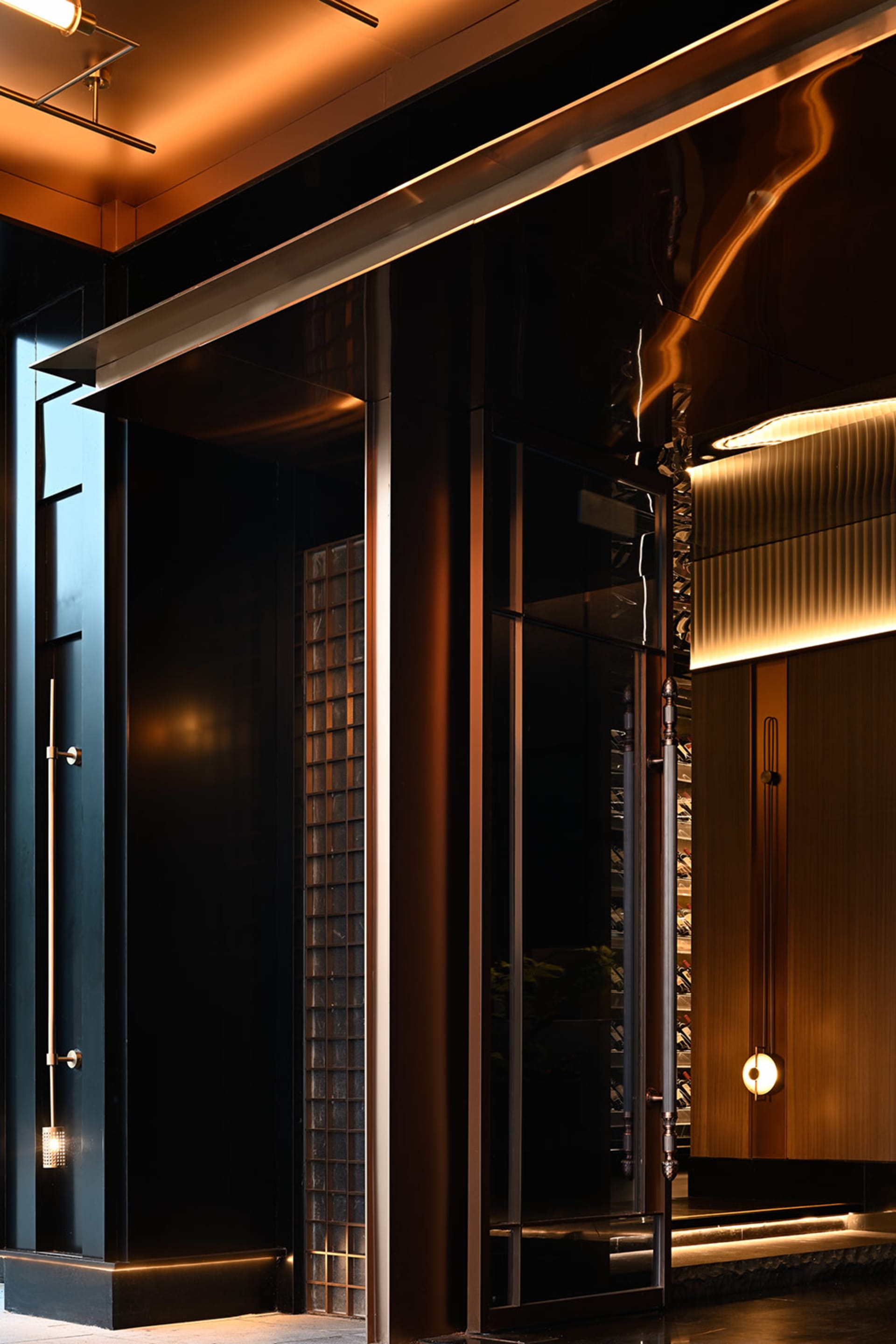 A hotel lobby with a brown color scheme, featuring a large glass door, two side doors, and potted plants along the hallway