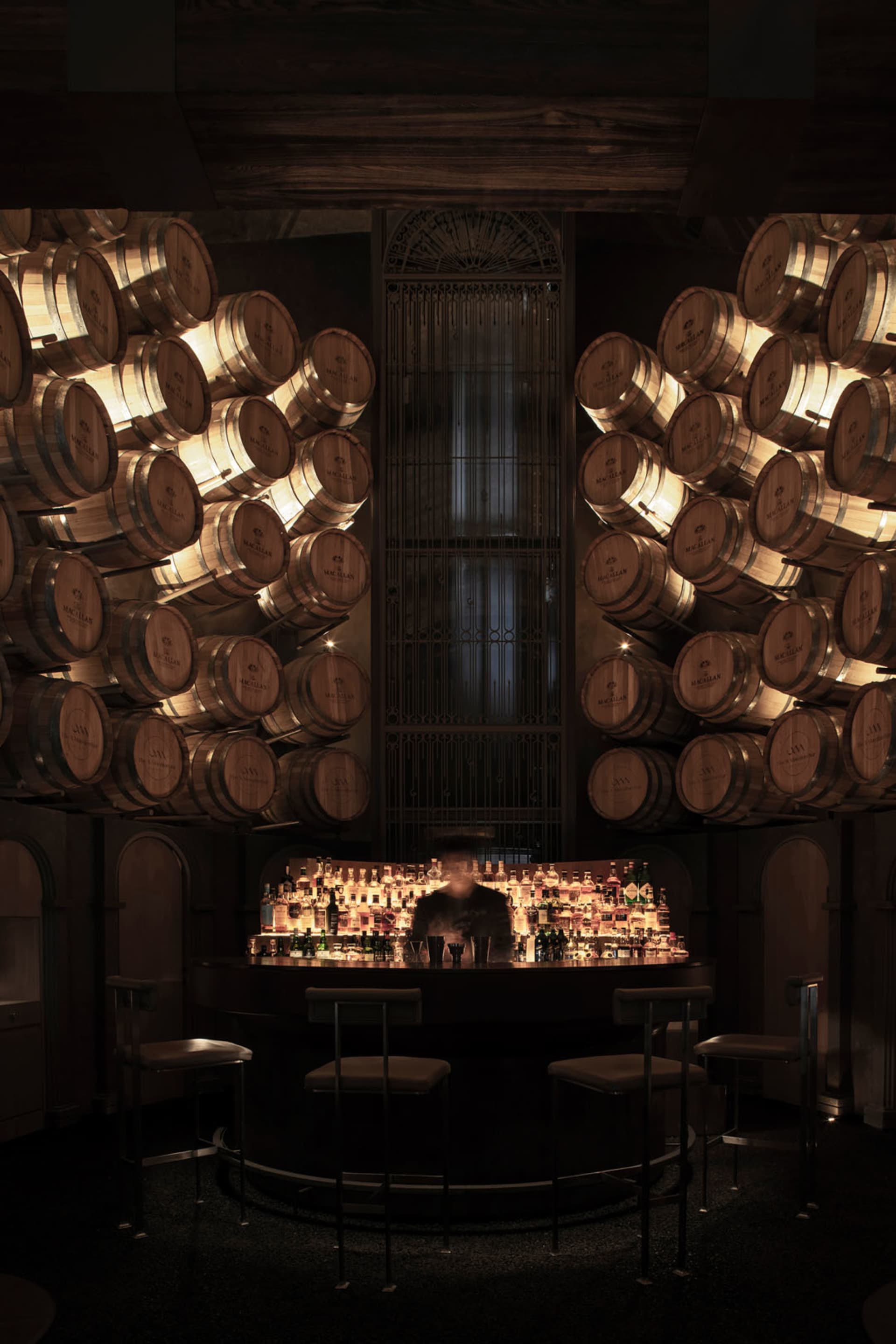 A cozy bar area with a wooden counter, wine barrels, and comfortable seating for patrons