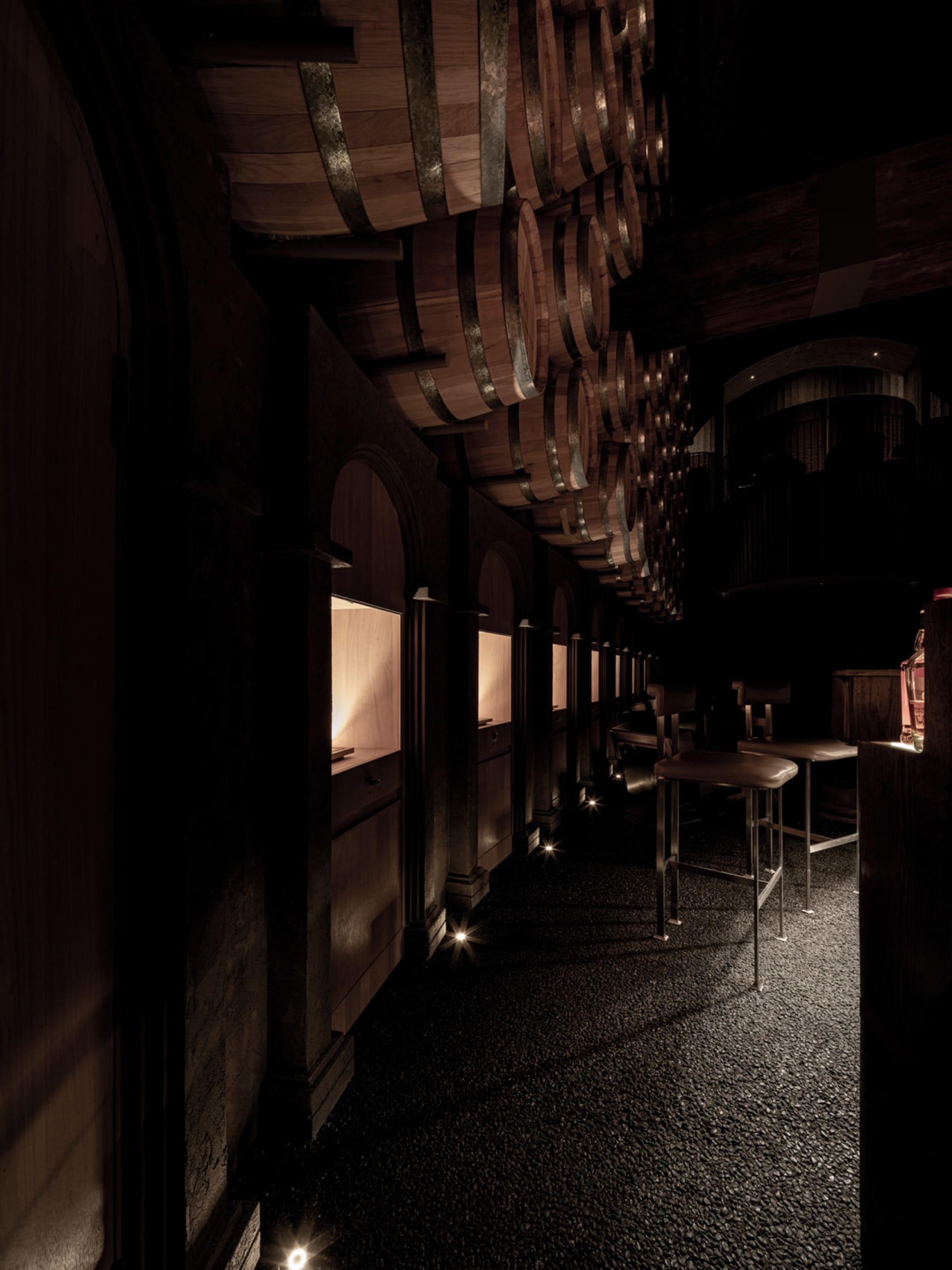 Dark bar area with wooden walls and floors, featuring chairs and a cozy atmosphere
