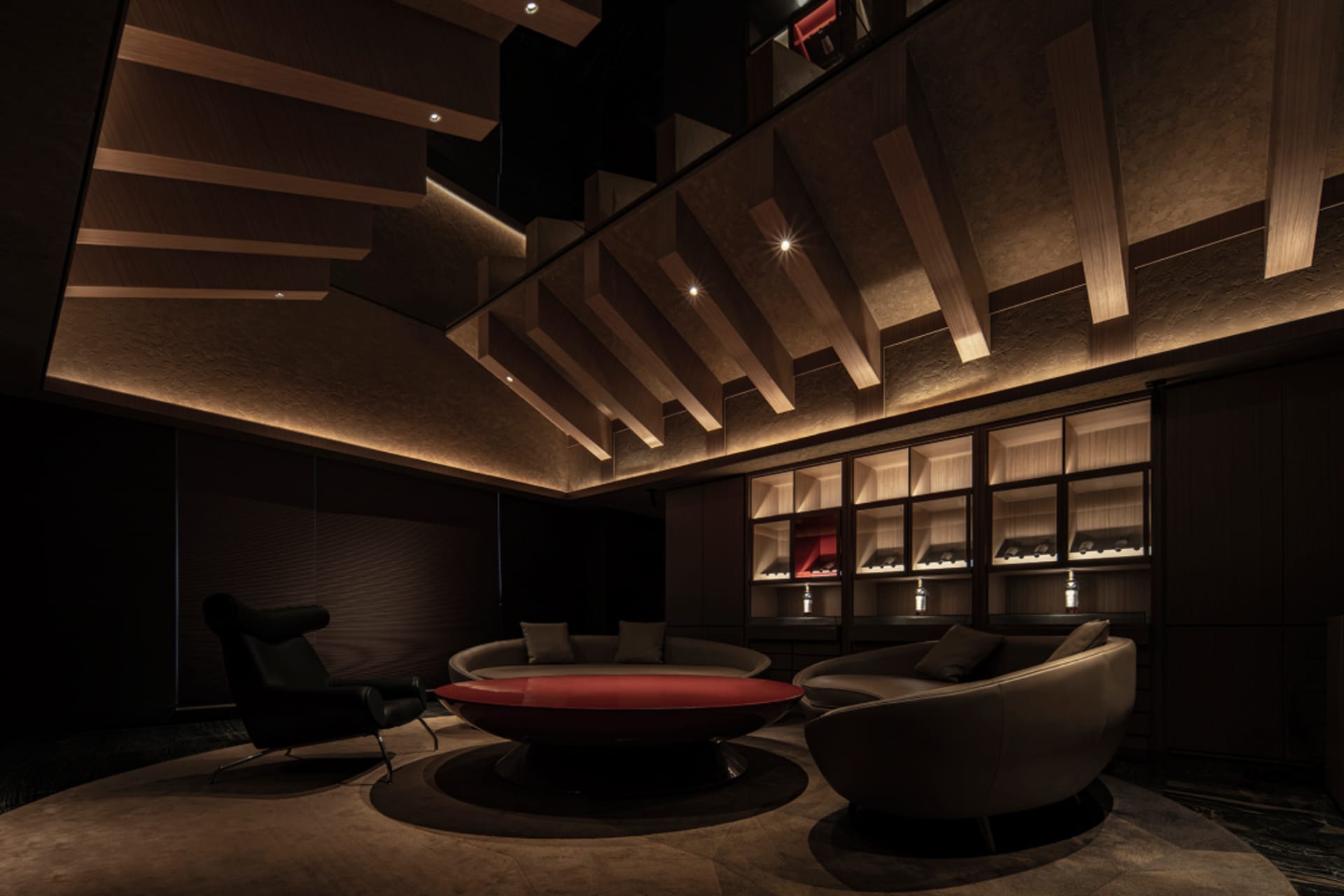 Elegant living space with a large red table, multiple couches, and two dining tables, well-lit with natural or artificial light