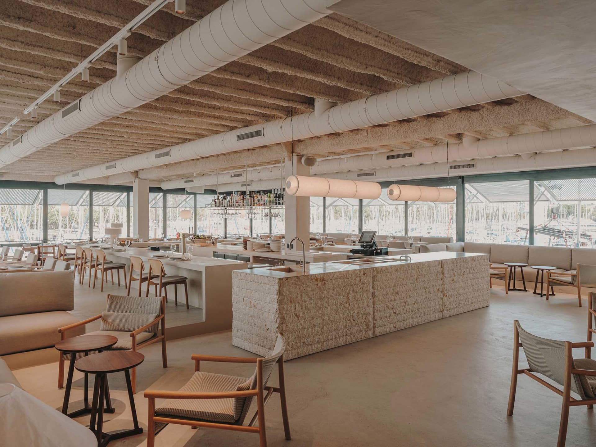 Inviting restaurant interior with a wooden bar, dining tables, and bottles on display, featuring a relaxed atmosphere for socializing and dining