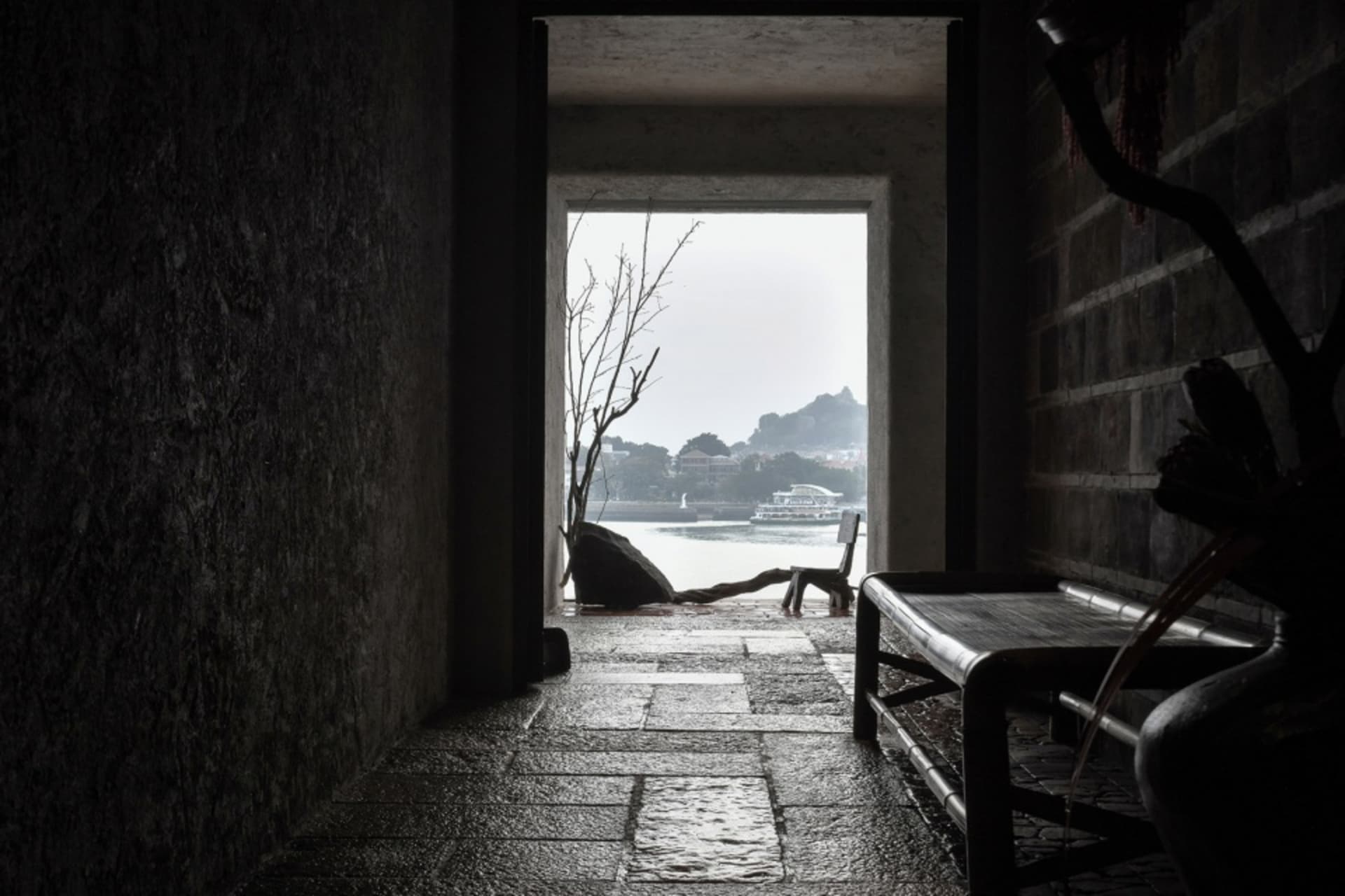 A small, dark room with a stone wall and a bench, creating a calm and quiet atmosphere