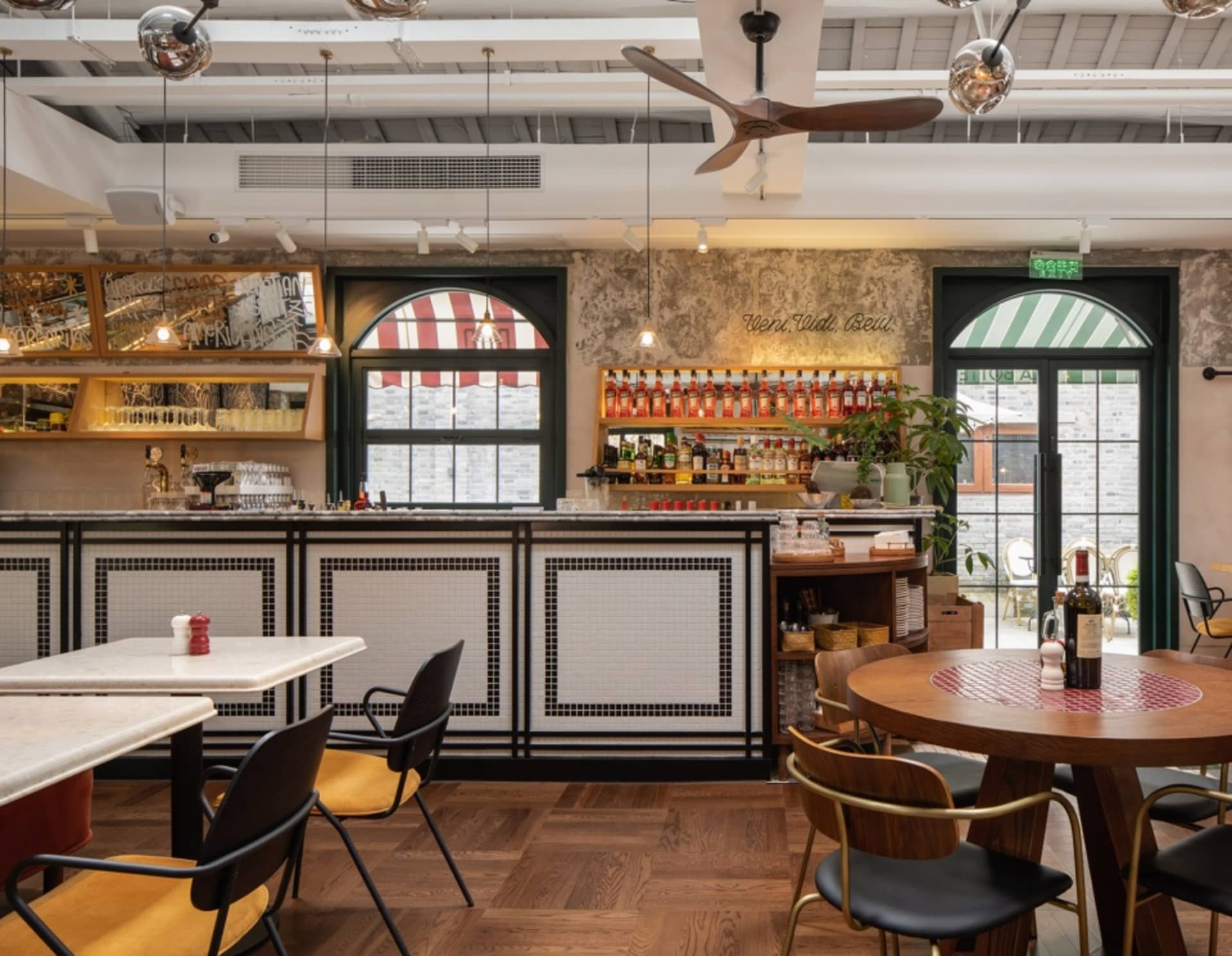 A cozy bar area with a wooden floor, black chairs, and a dining table, featuring bottles on the countertop and a welcoming atmosphere