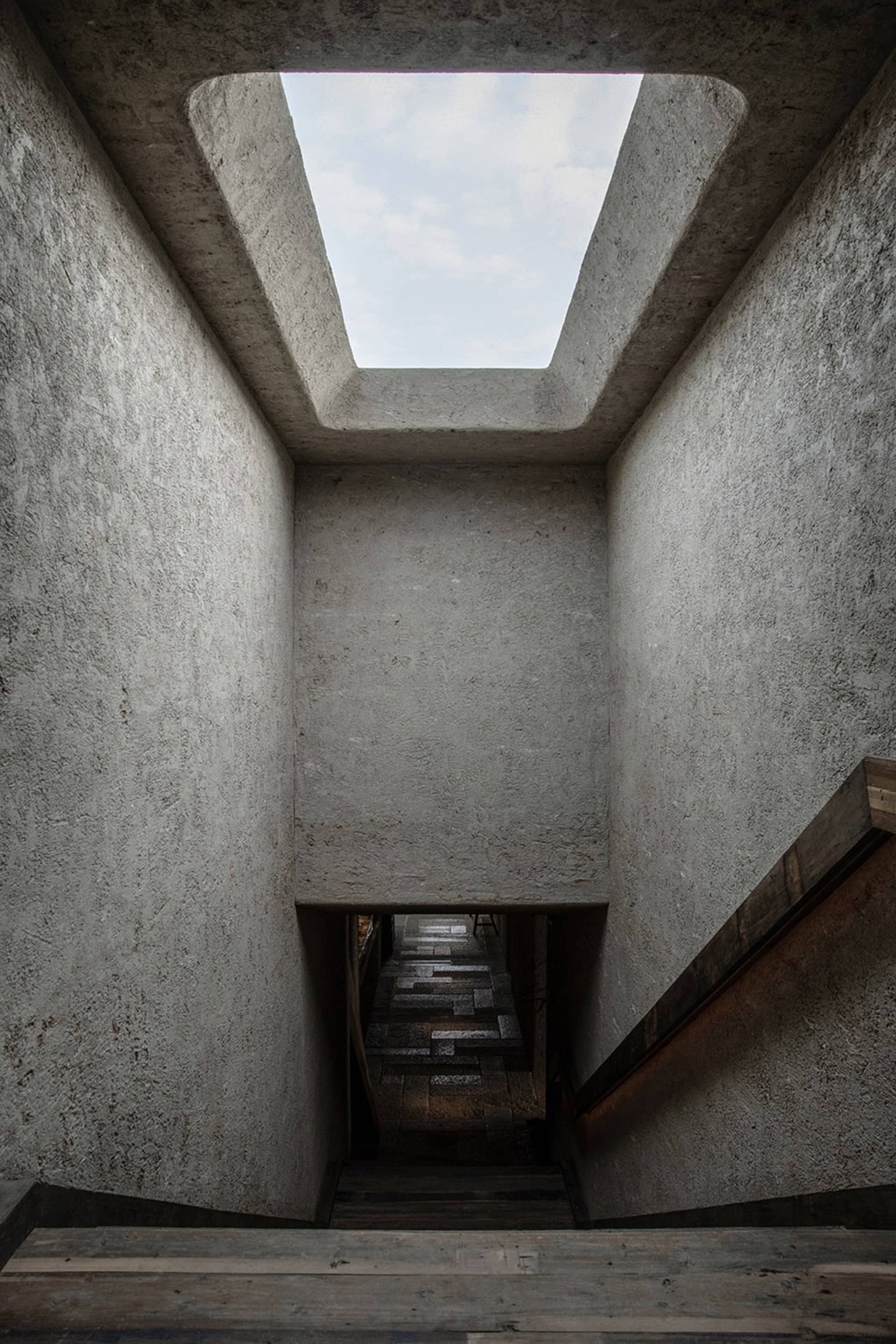 A dimly lit stairwell with stone steps, leading to a doorway in a traditional building with a focus on functionality