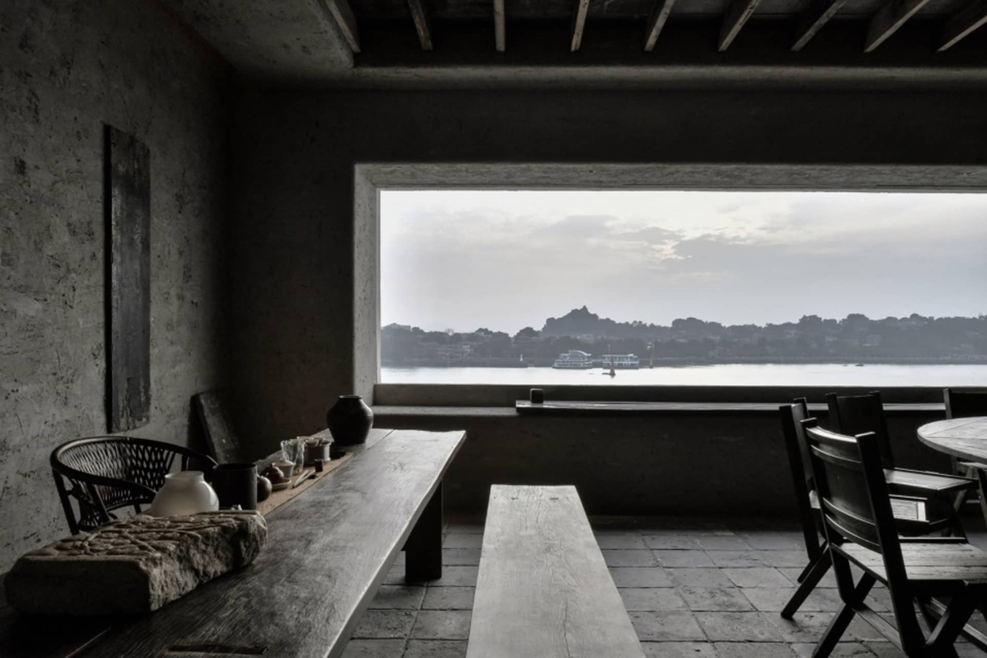 A well-lit dining space with a table, chairs, and decorative items, featuring boats in the background, creating a cozy and inviting atmosphere