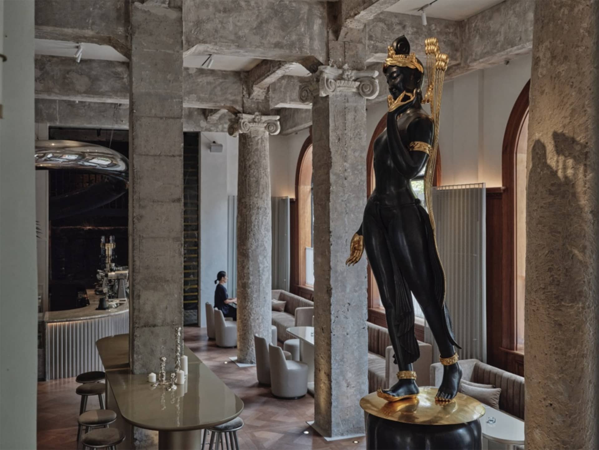 一座華麗的餐廳，腳踏上擺放精緻雕像，周圍環繞餐椅與餐桌，呈現奢華的室內設計風格