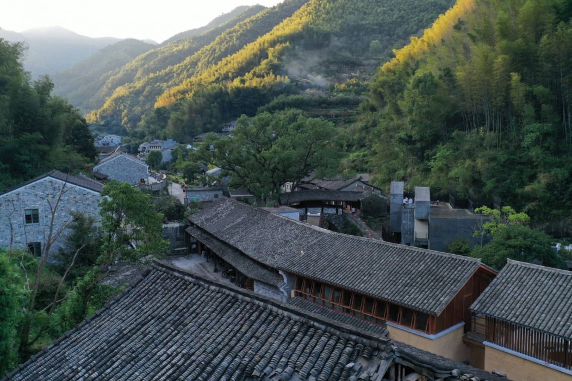 A quaint village with stone and wood buildings, featuring wooden roofs and stone walls, surrounded by trees and natural scenery