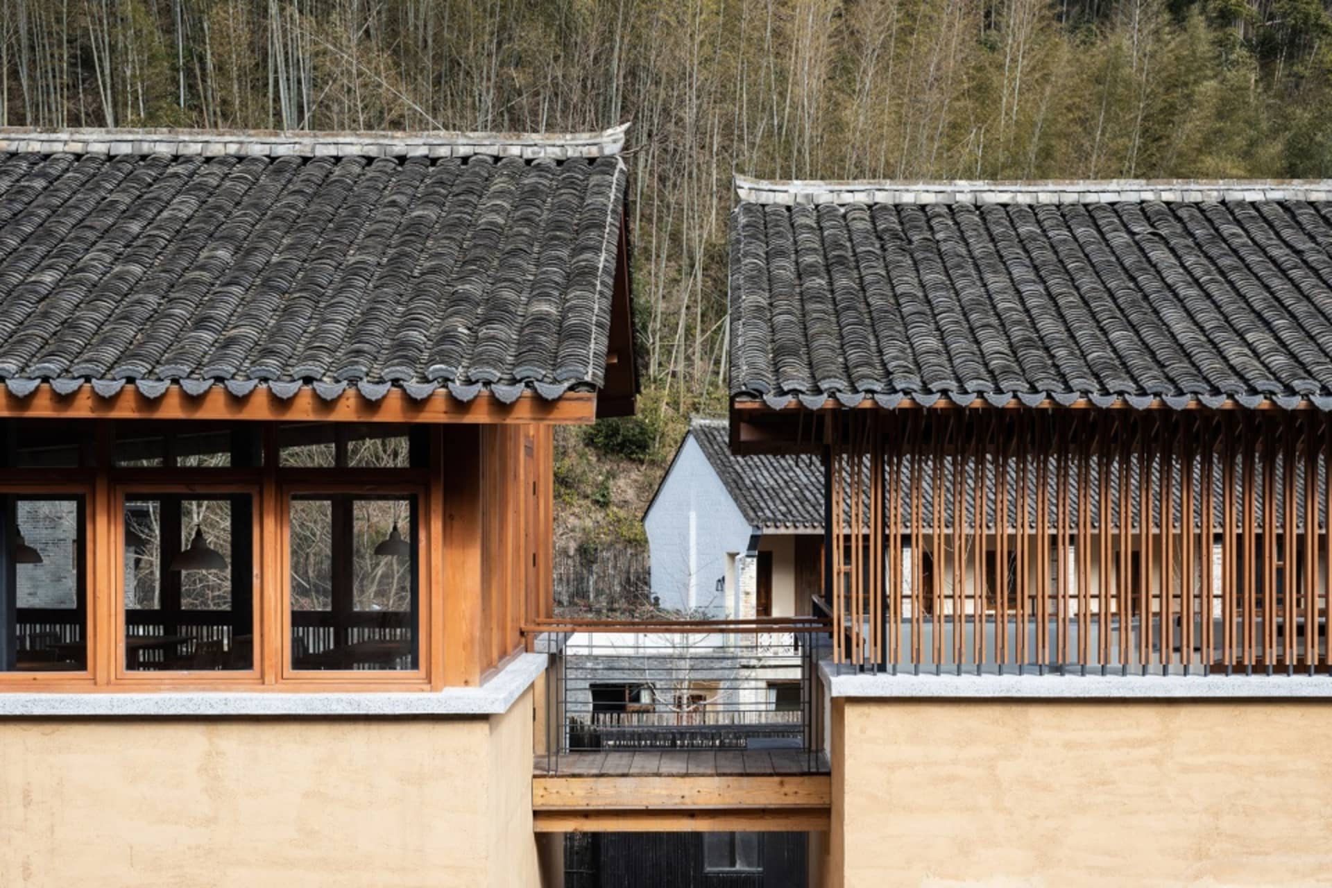Asian-style house with two connected sections, wooden bridge, and balcony, featuring traditional roof designs and wooden elements